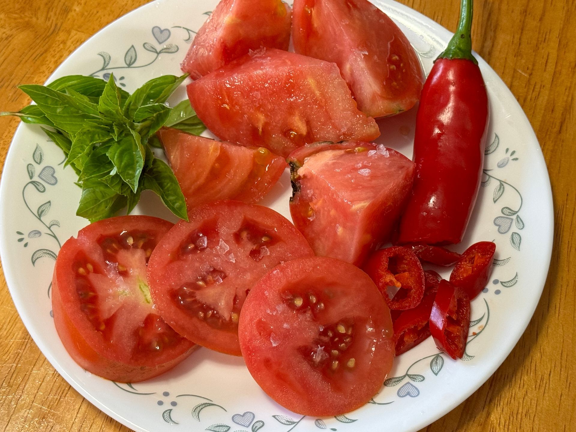 A salad with tomatoes , croutons , onions and other vegetables in a bowl