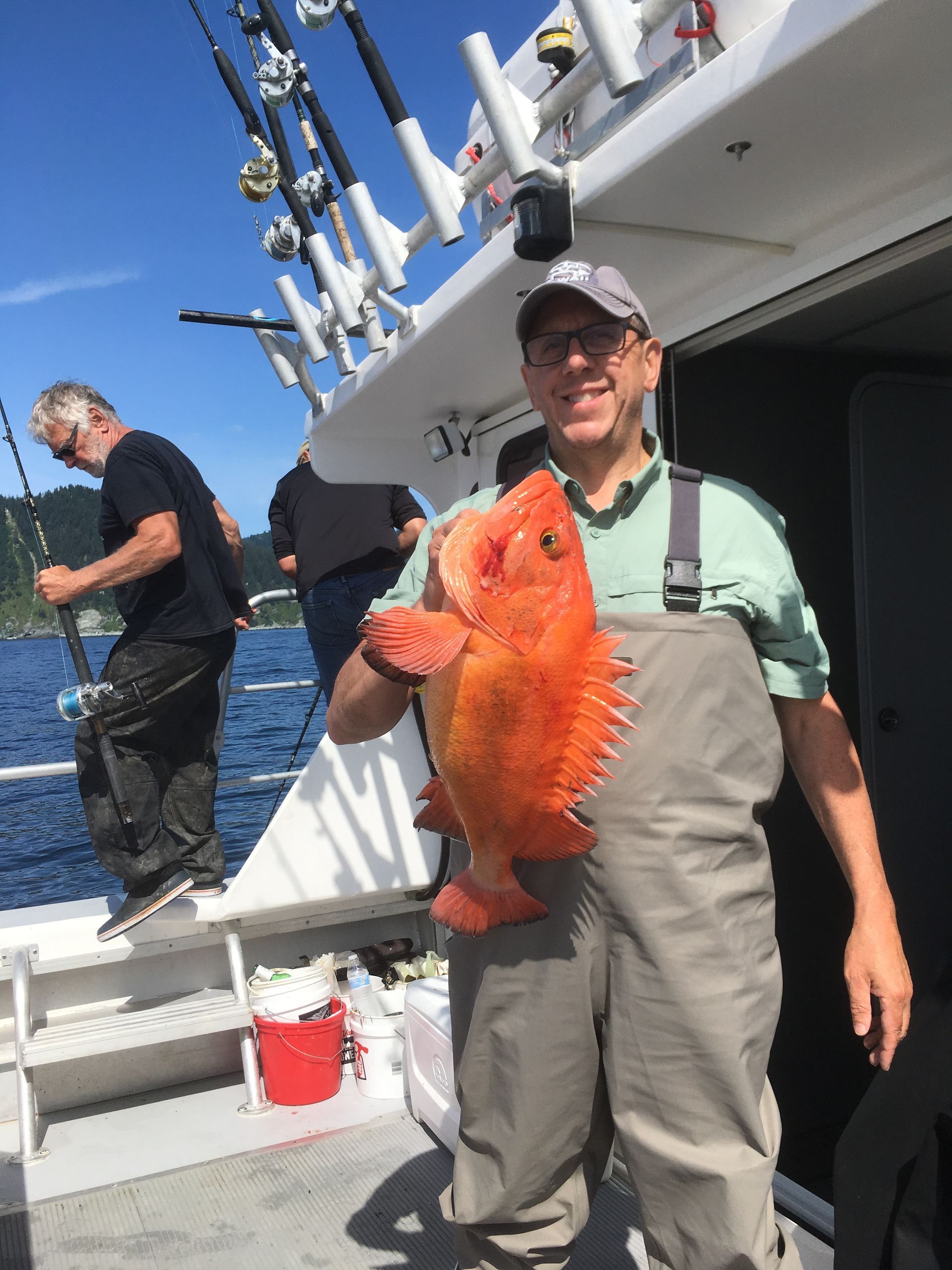 A man is holding a large red fish on a boat