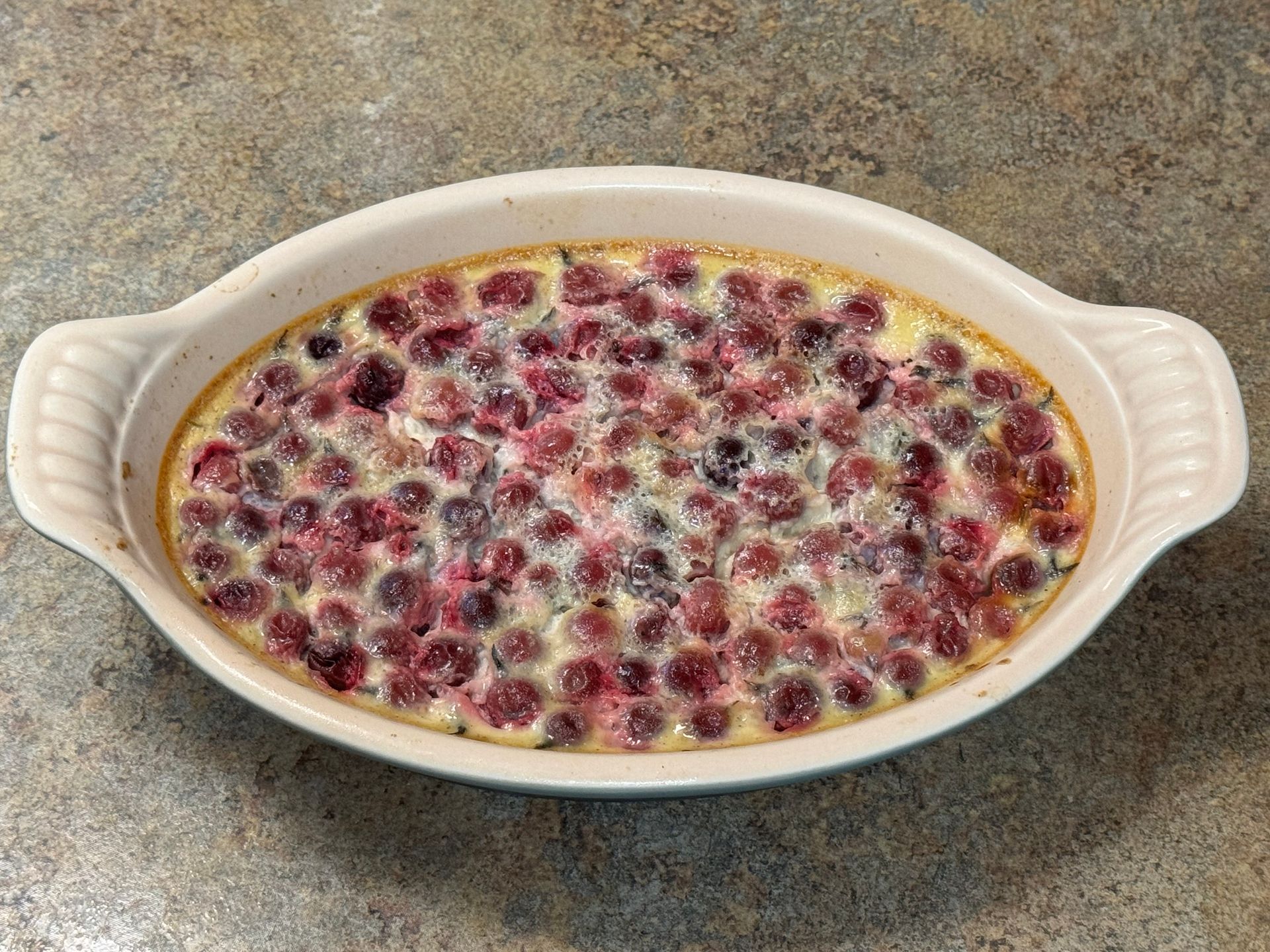 A white casserole dish filled with cranberries and whipped cream