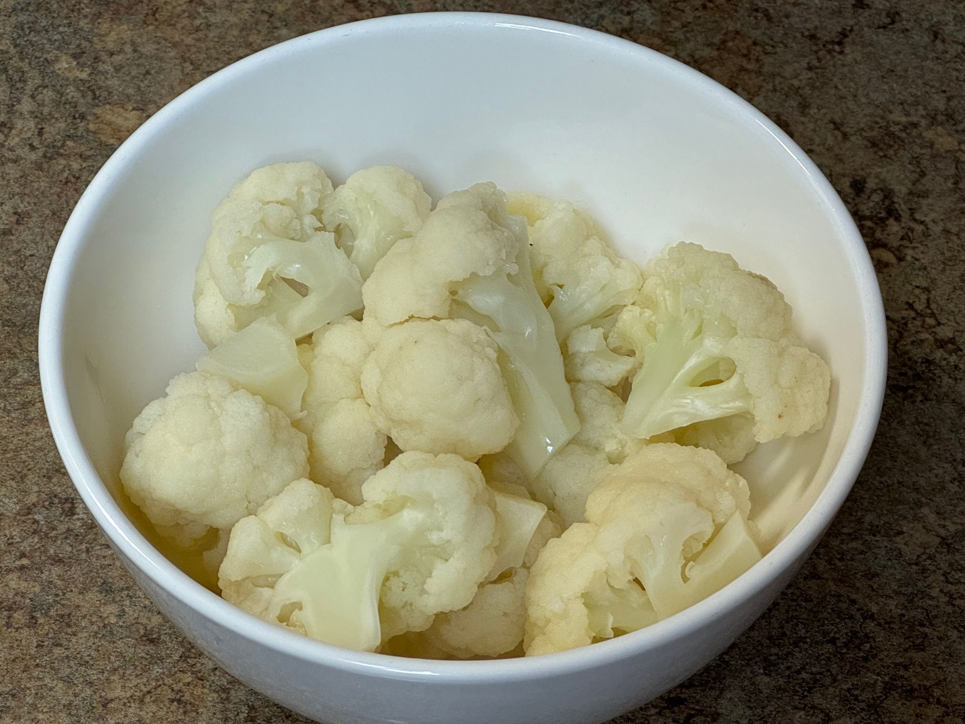 A bowl of cauliflower is sitting on a table.