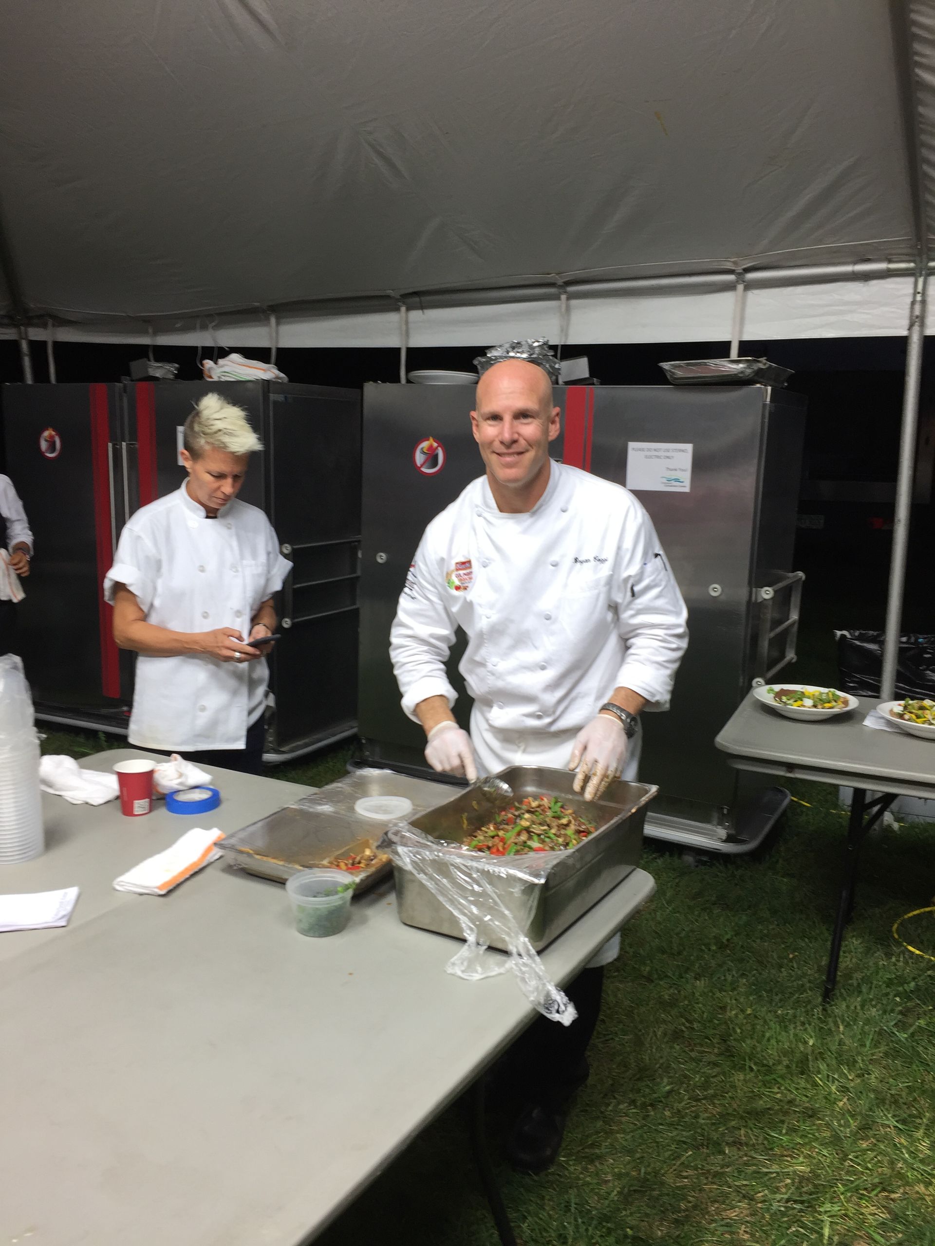 A man in a chef 's uniform is preparing food on a table