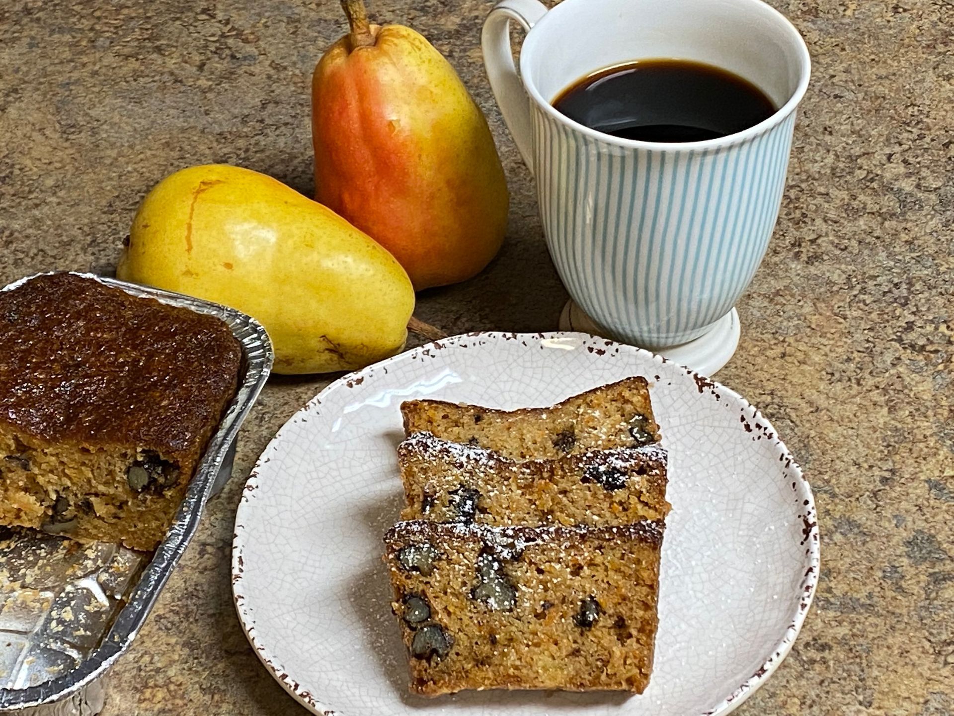 A slice of banana bread is on a plate next to a cup of coffee and pears.