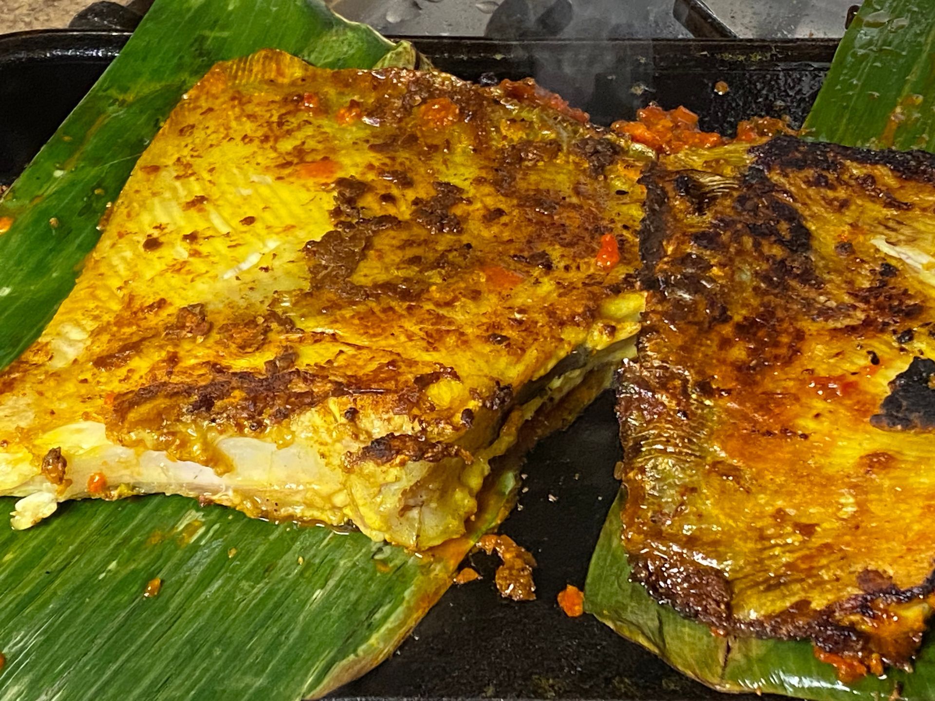 A close up of two pieces of food on a banana leaf