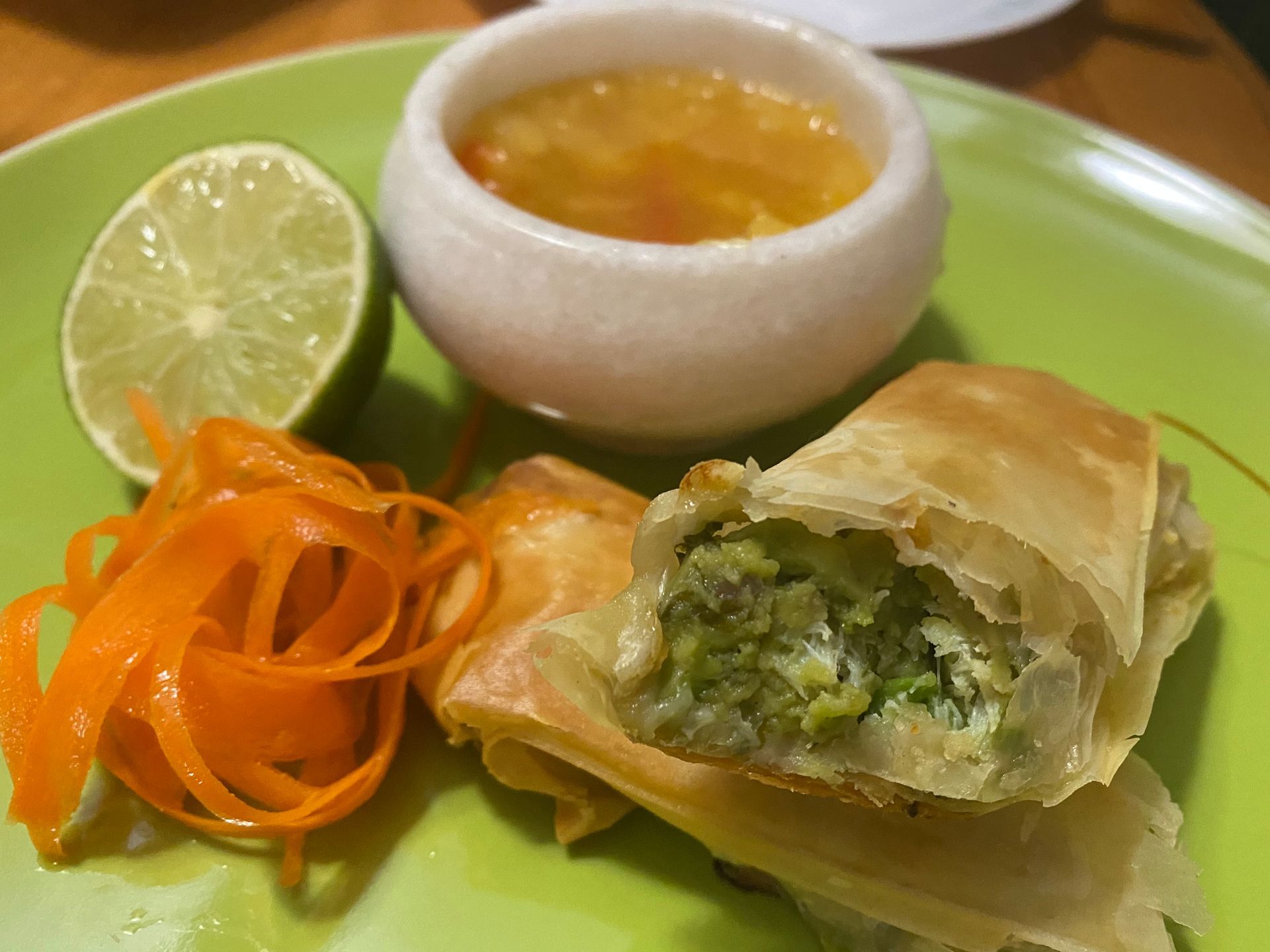 A green plate topped with food and a bowl of dipping sauce