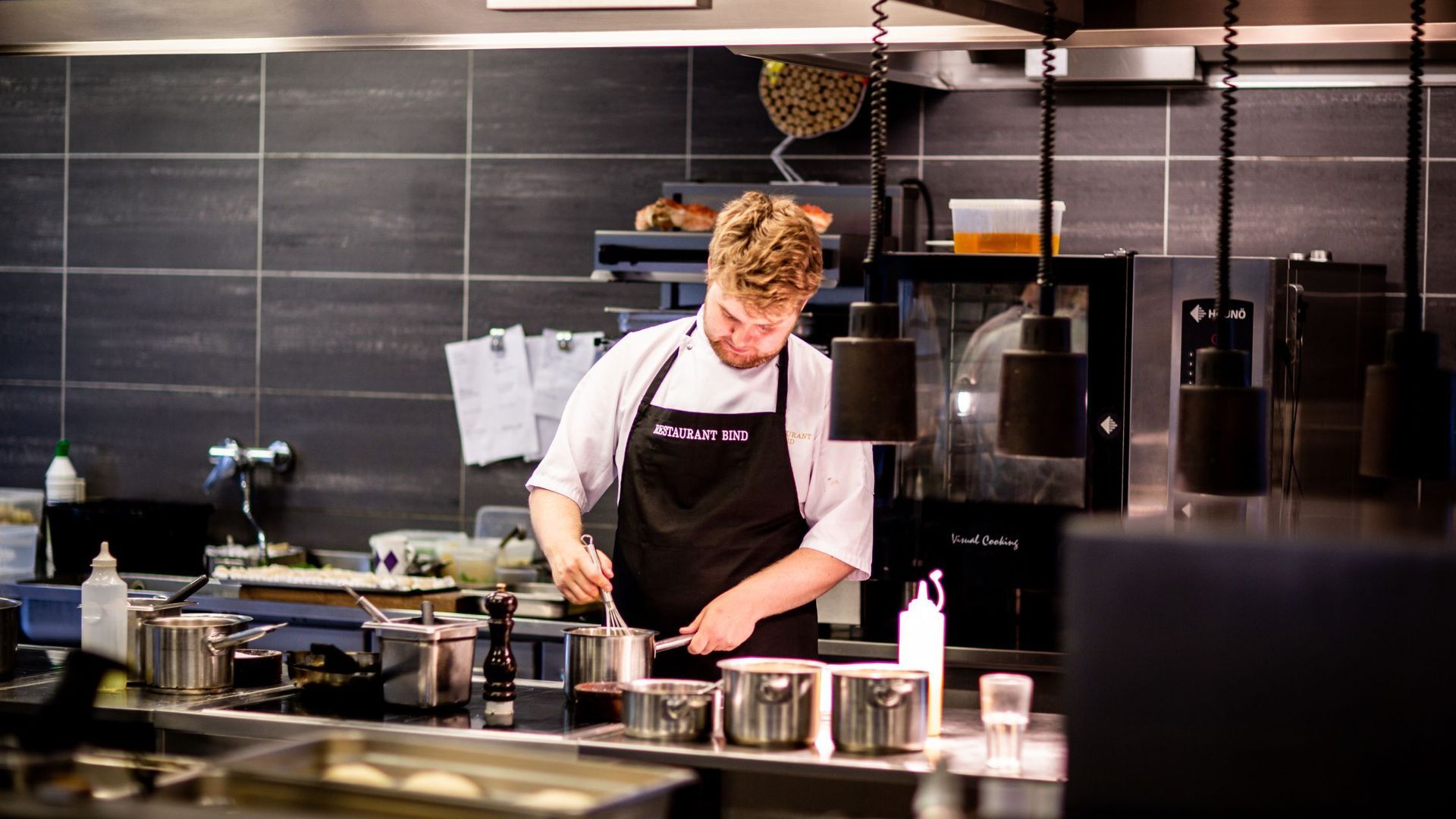 A chef in an apron is preparing food in a kitchen culinary innovation consultant.