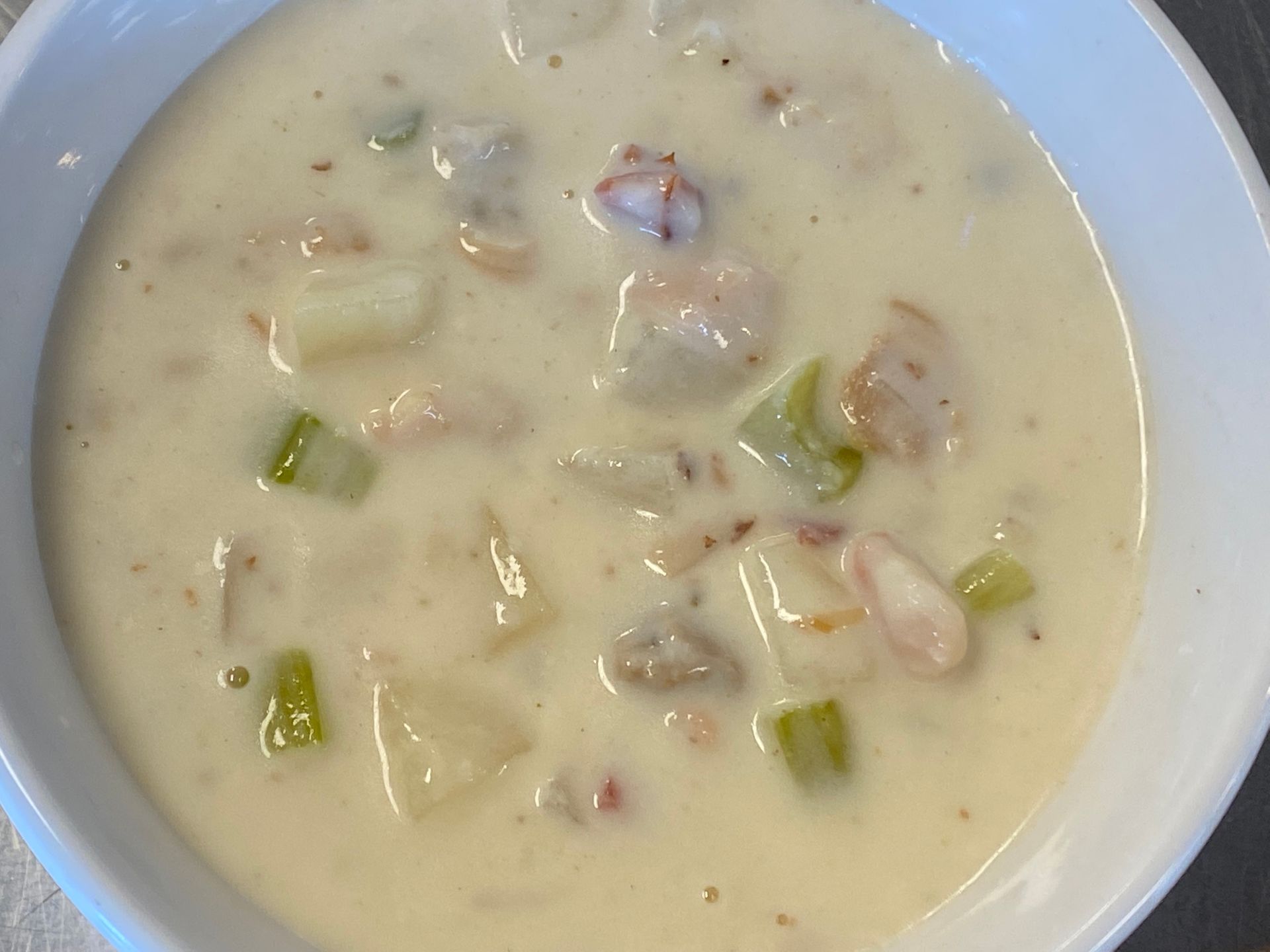 A close up of a bowl of soup with shrimp and potatoes.