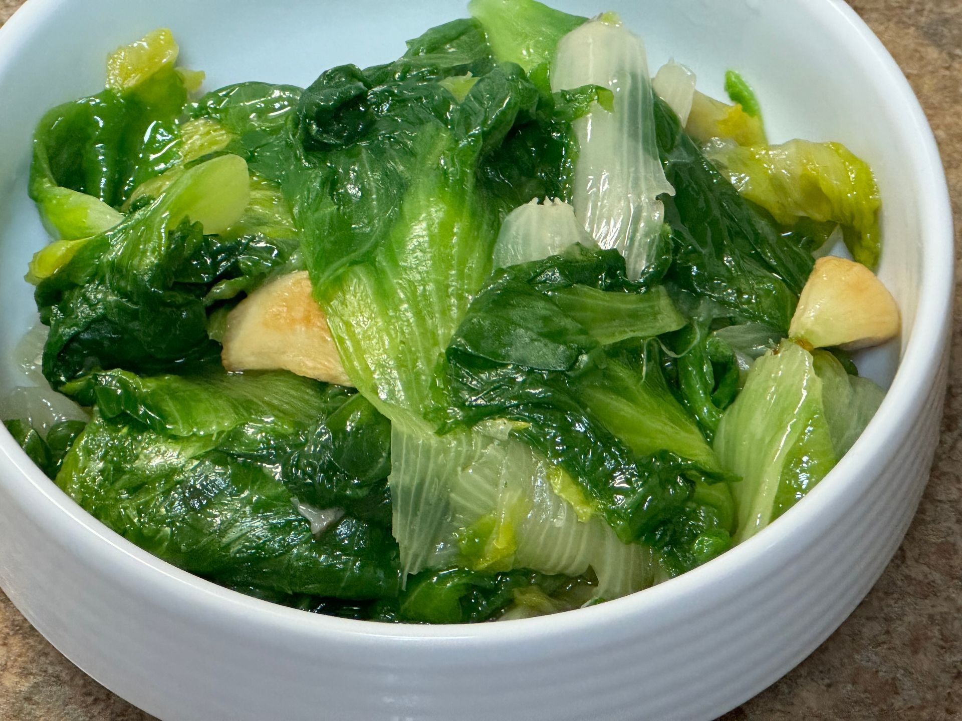 A white bowl filled with lettuce and other vegetables