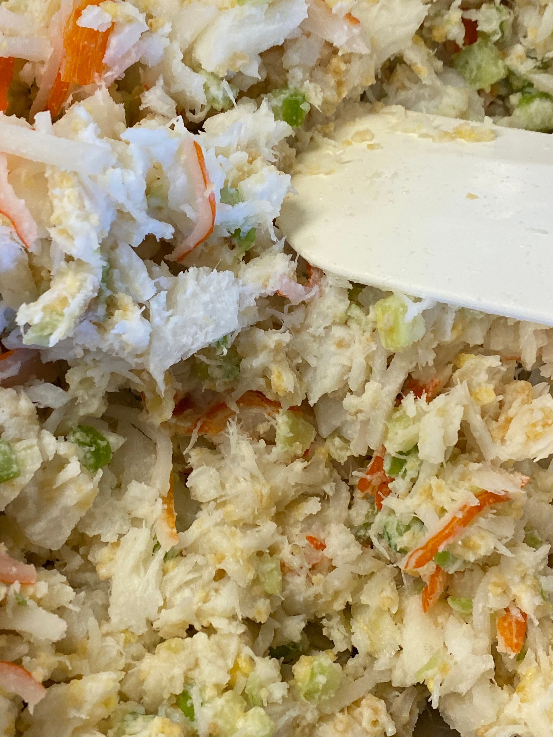 A close up of a crab salad with a spoon in it.