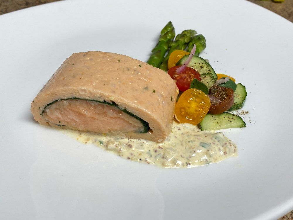 A white plate topped with a piece of salmon and vegetables