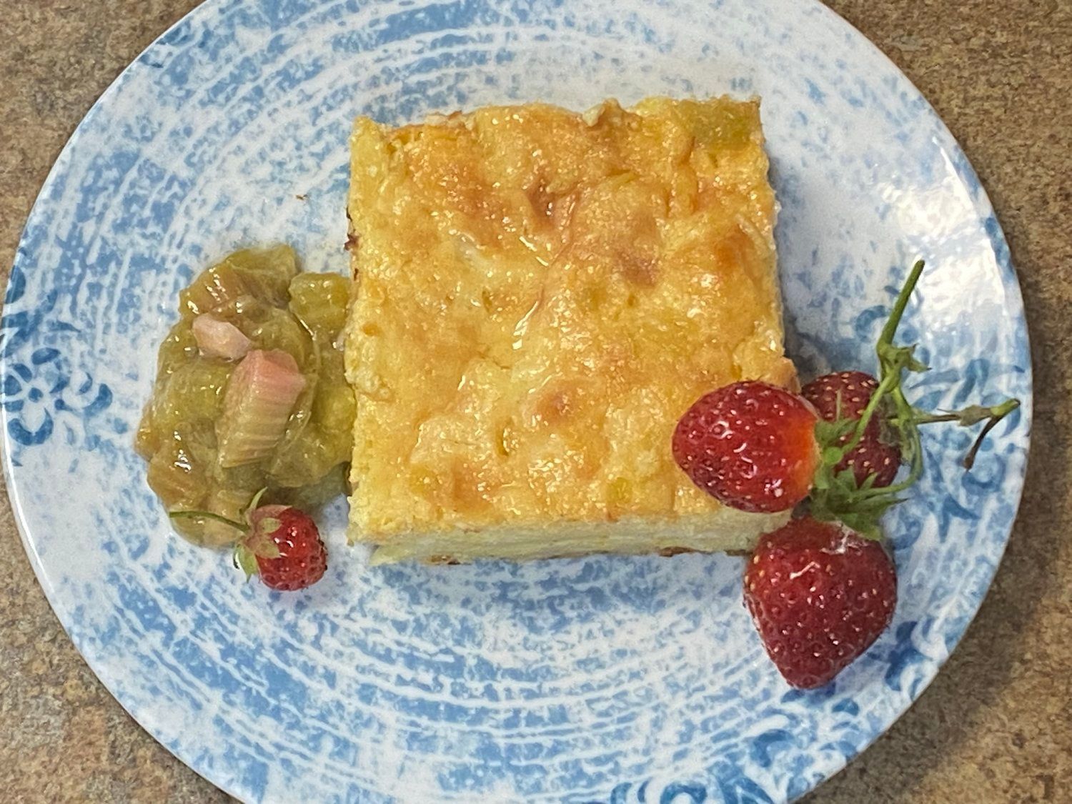 A blue and white plate topped with a piece of cake and strawberries.