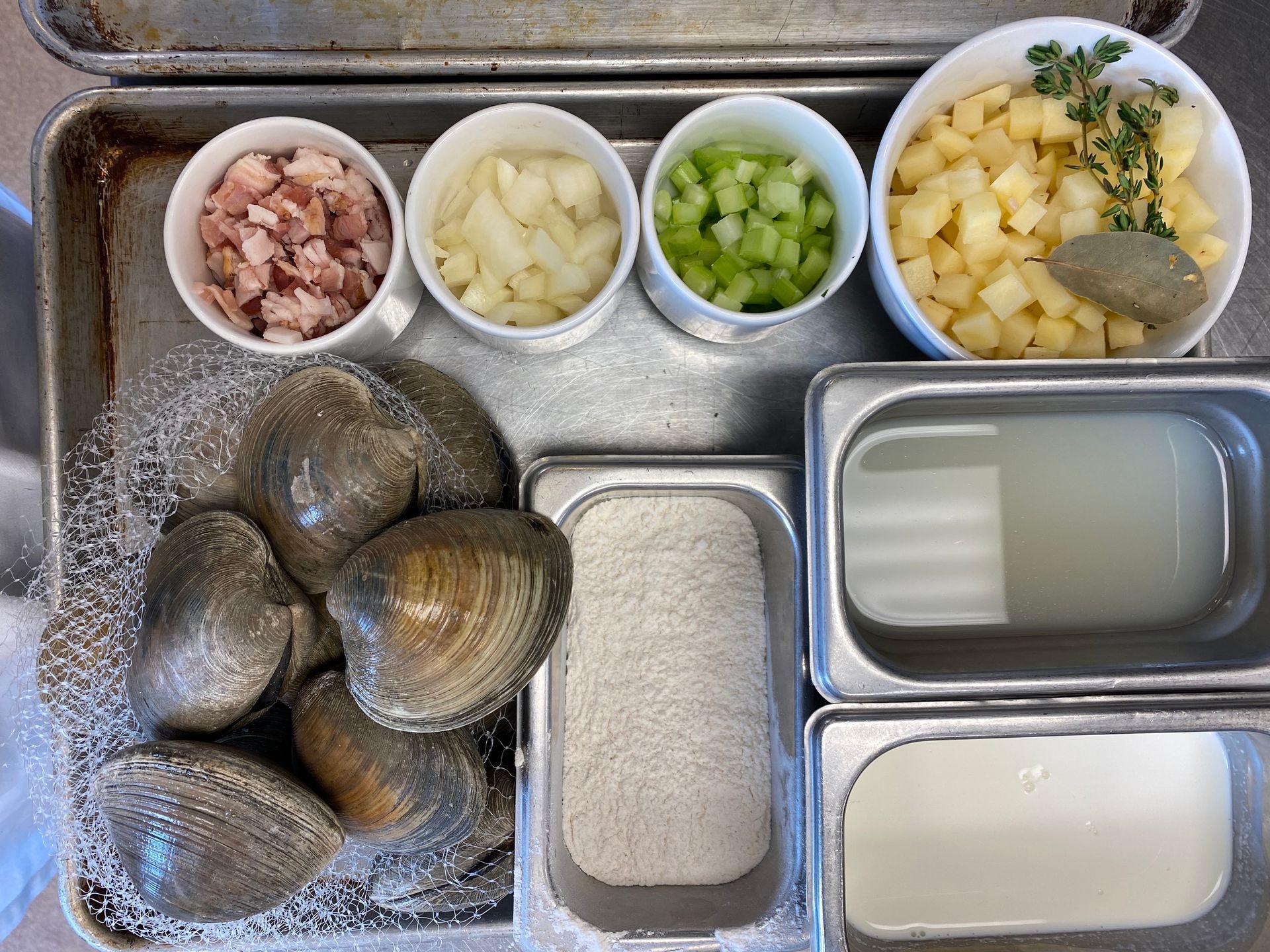 A pan filled with clams , onions , celery , and other ingredients.