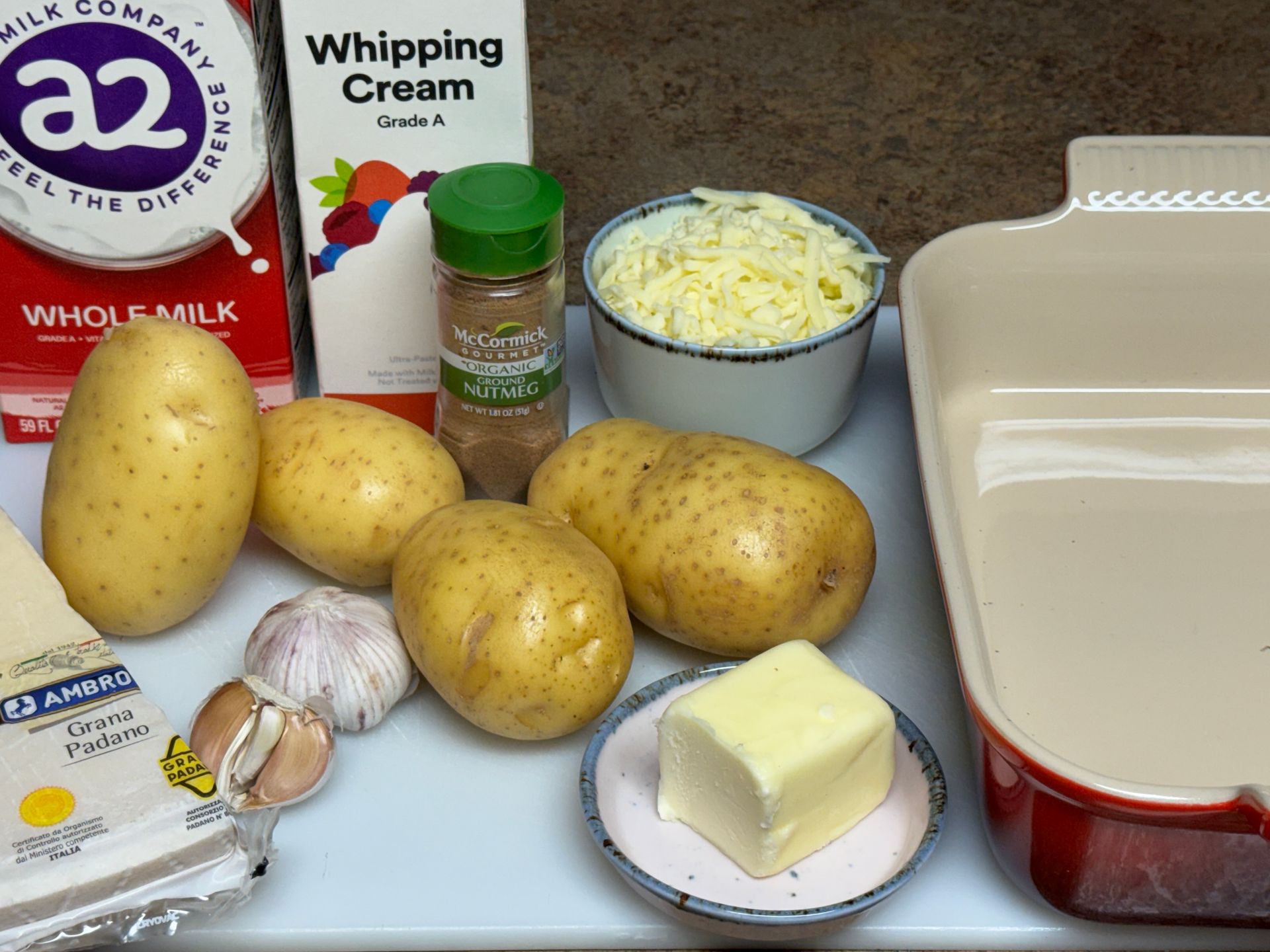 Potatoes , butter , salt and pepper are on a blue cutting board.