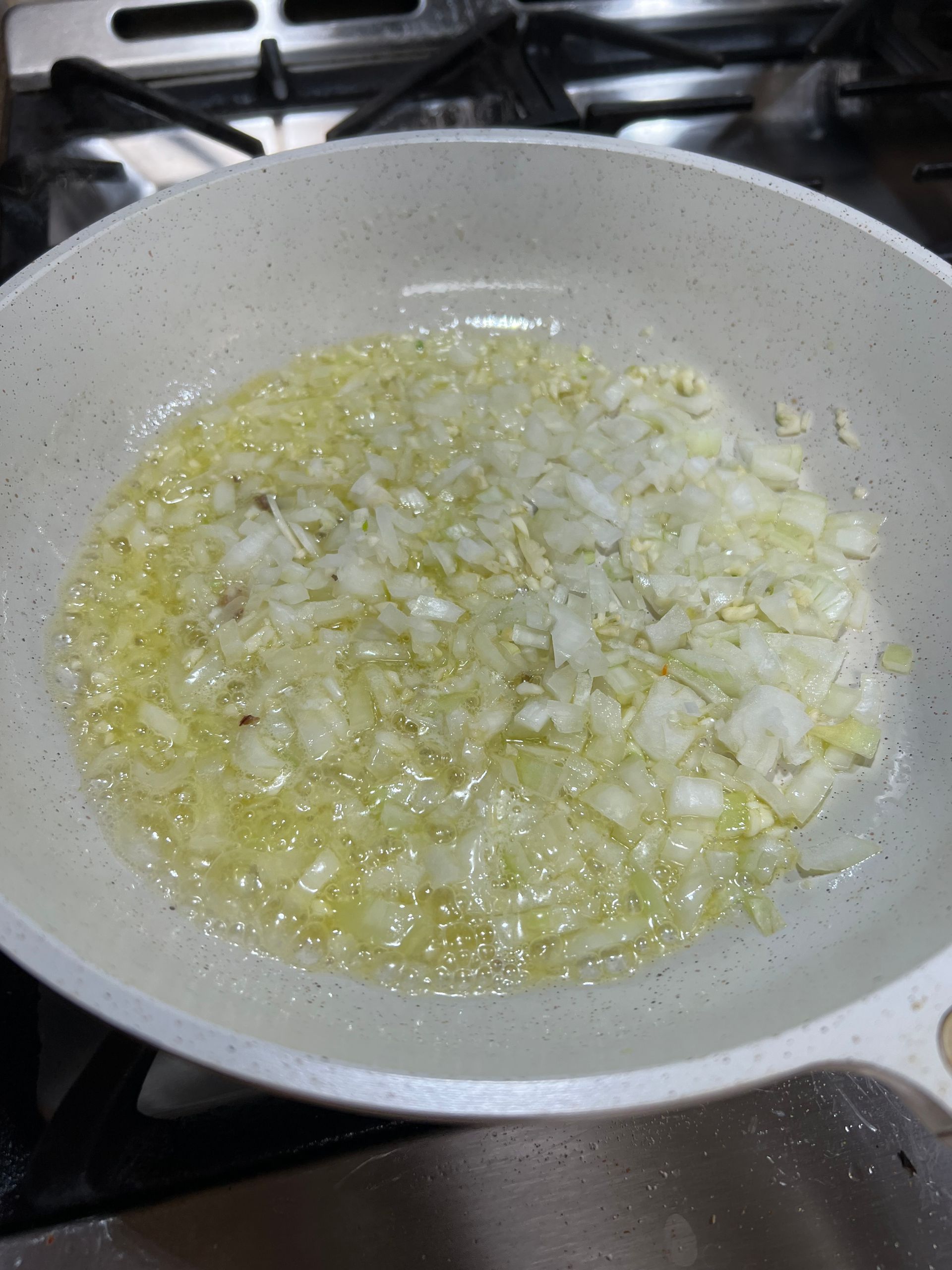 A pan filled with chopped onions is cooking on a stove.