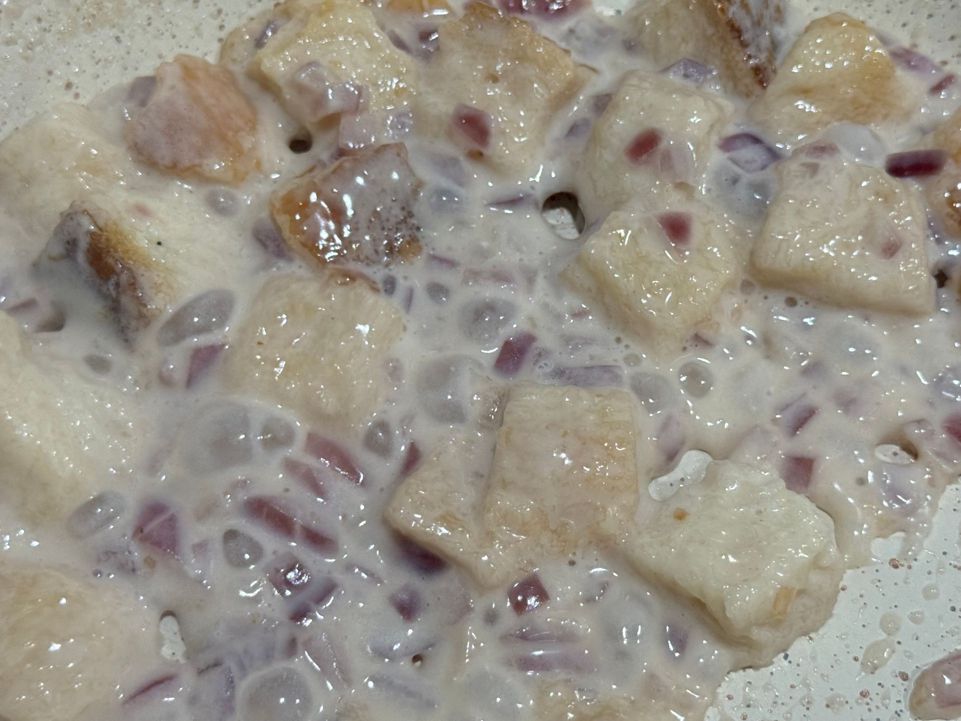 A close up of a white sauce with bread and onions