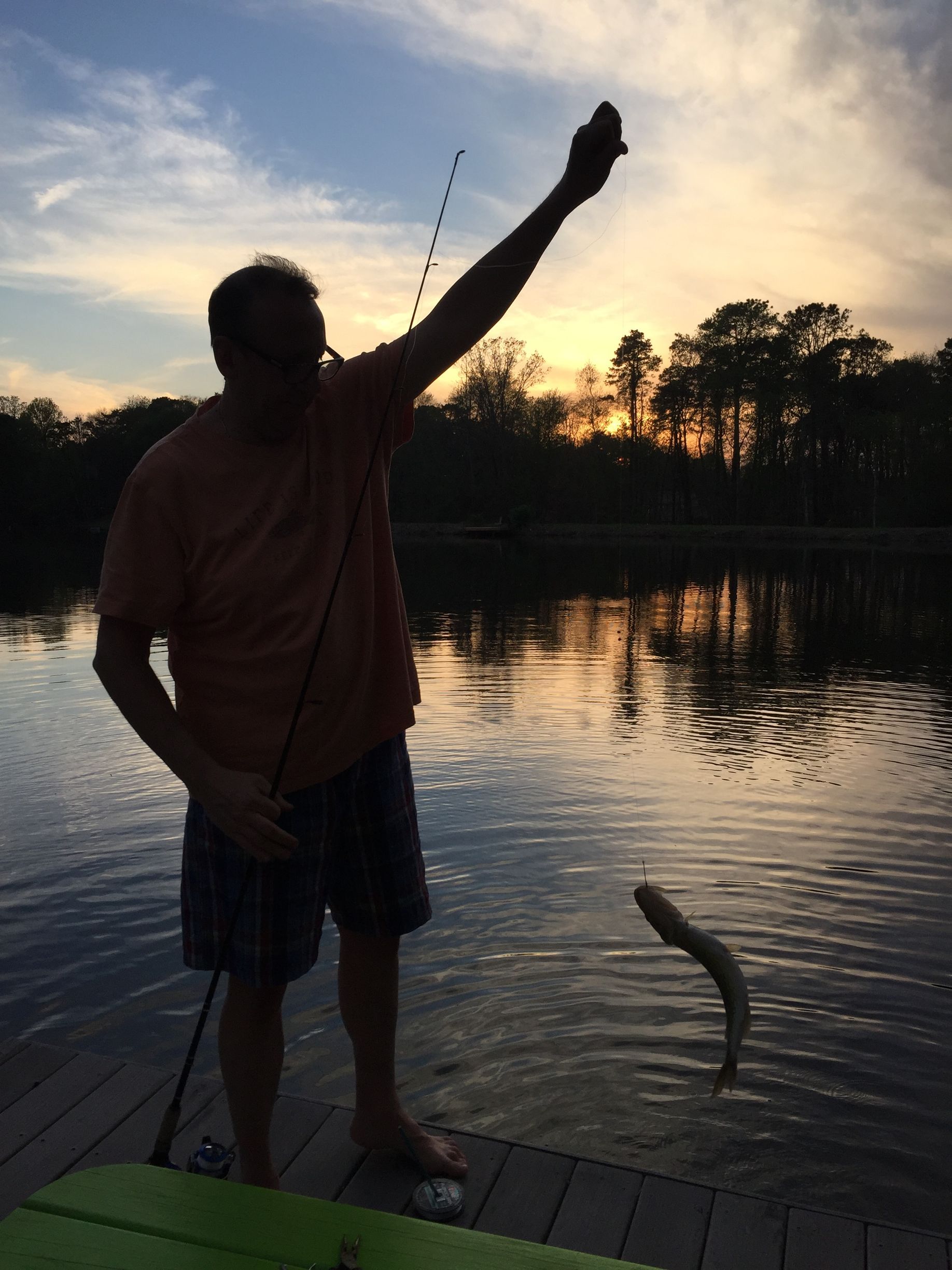 A man standing on a dock holding a fish in his hand