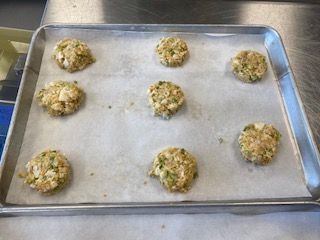 A pan filled with crab cakes is sitting on a table.