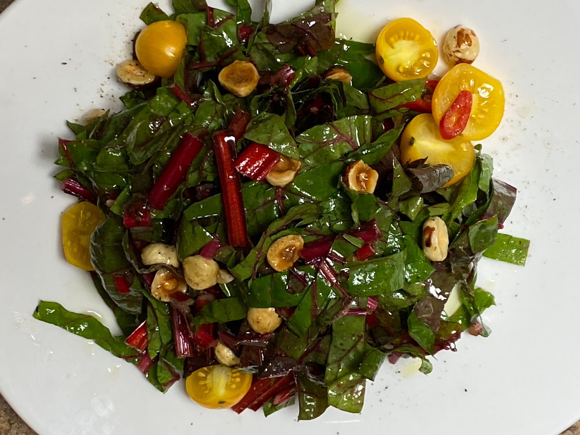 A salad with nuts and tomatoes on a white plate