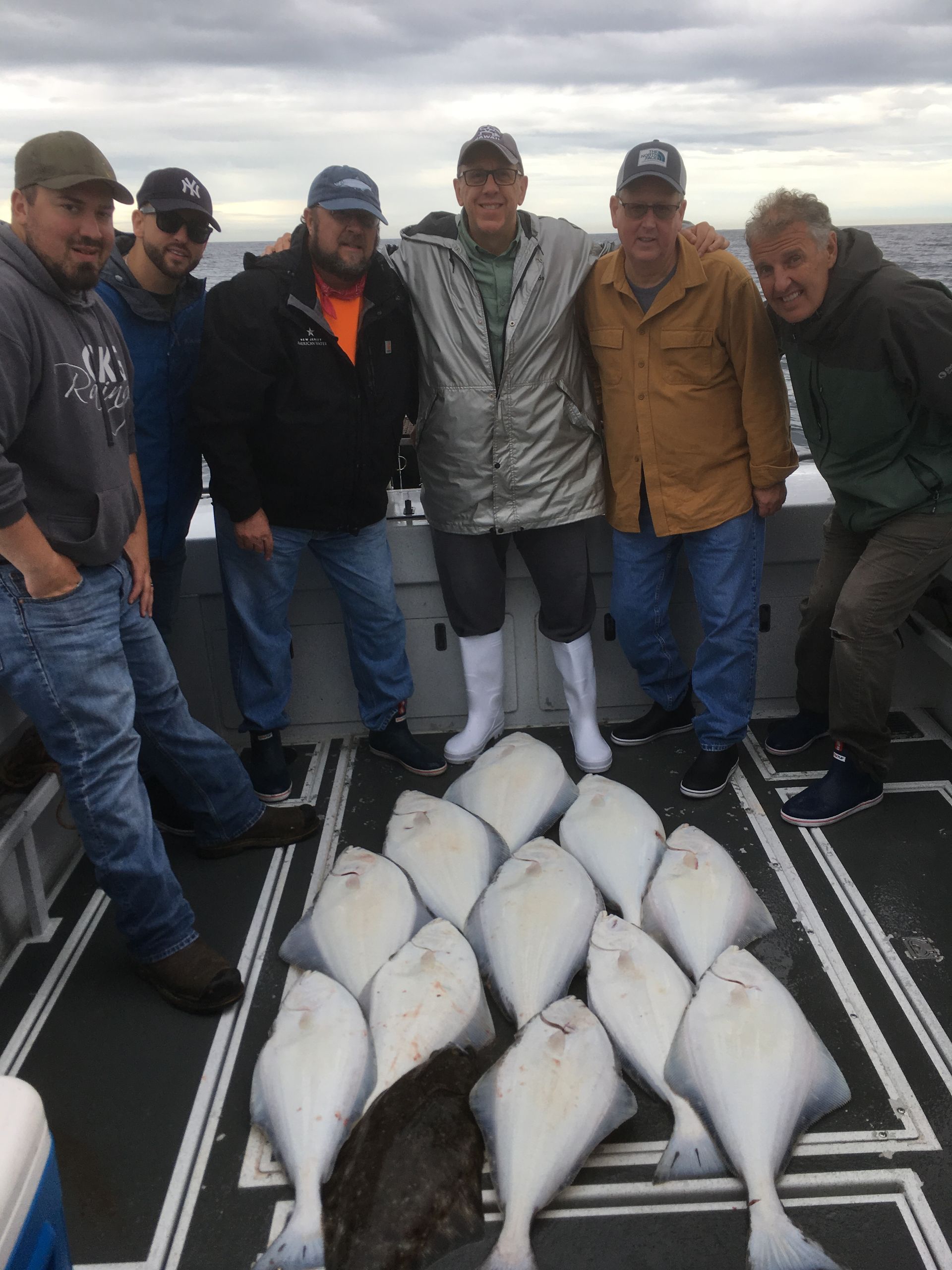 A group of men are posing for a picture on a boat with fish