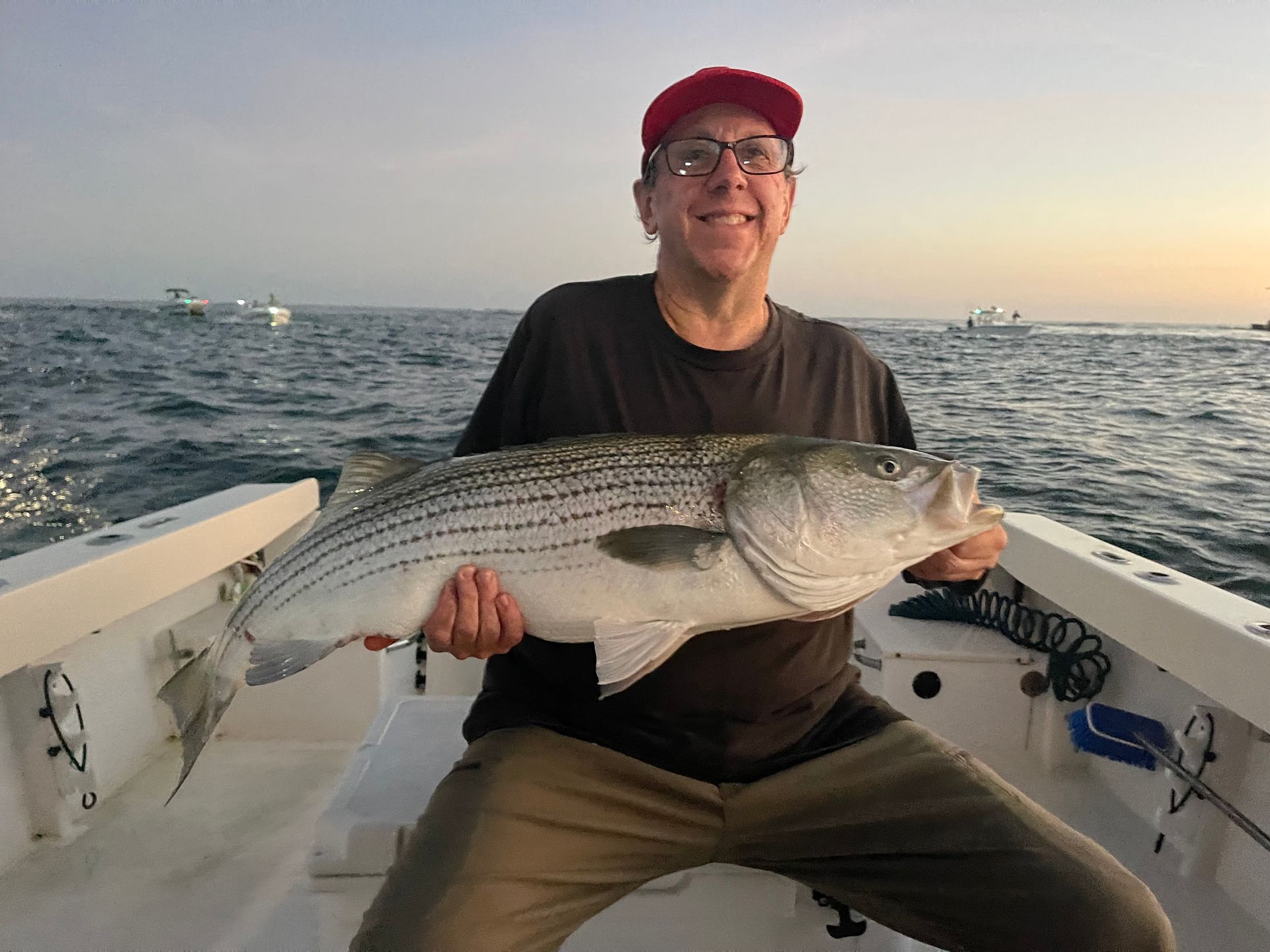 A man is sitting on a boat holding a large fish.