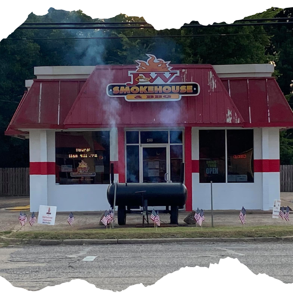 A white building with a red awning that says smokehouse