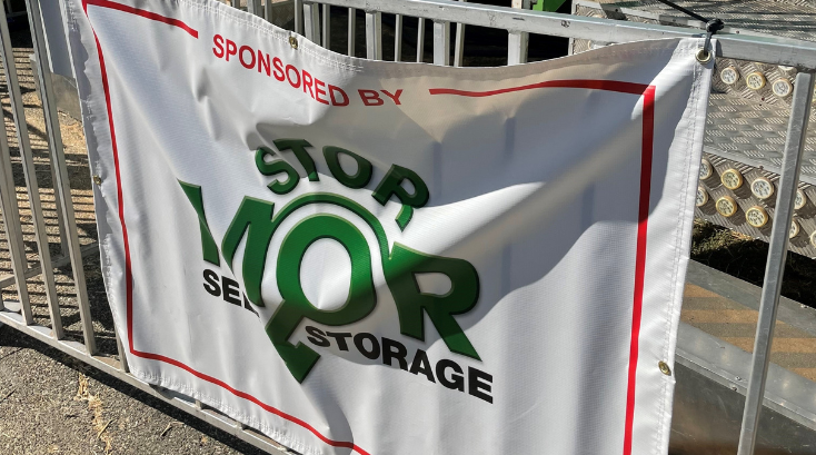 A stop mor sign is hanging on a metal fence.
