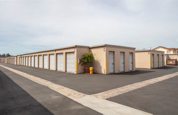 A row of storage units with a fire hydrant in the middle of the parking lot.