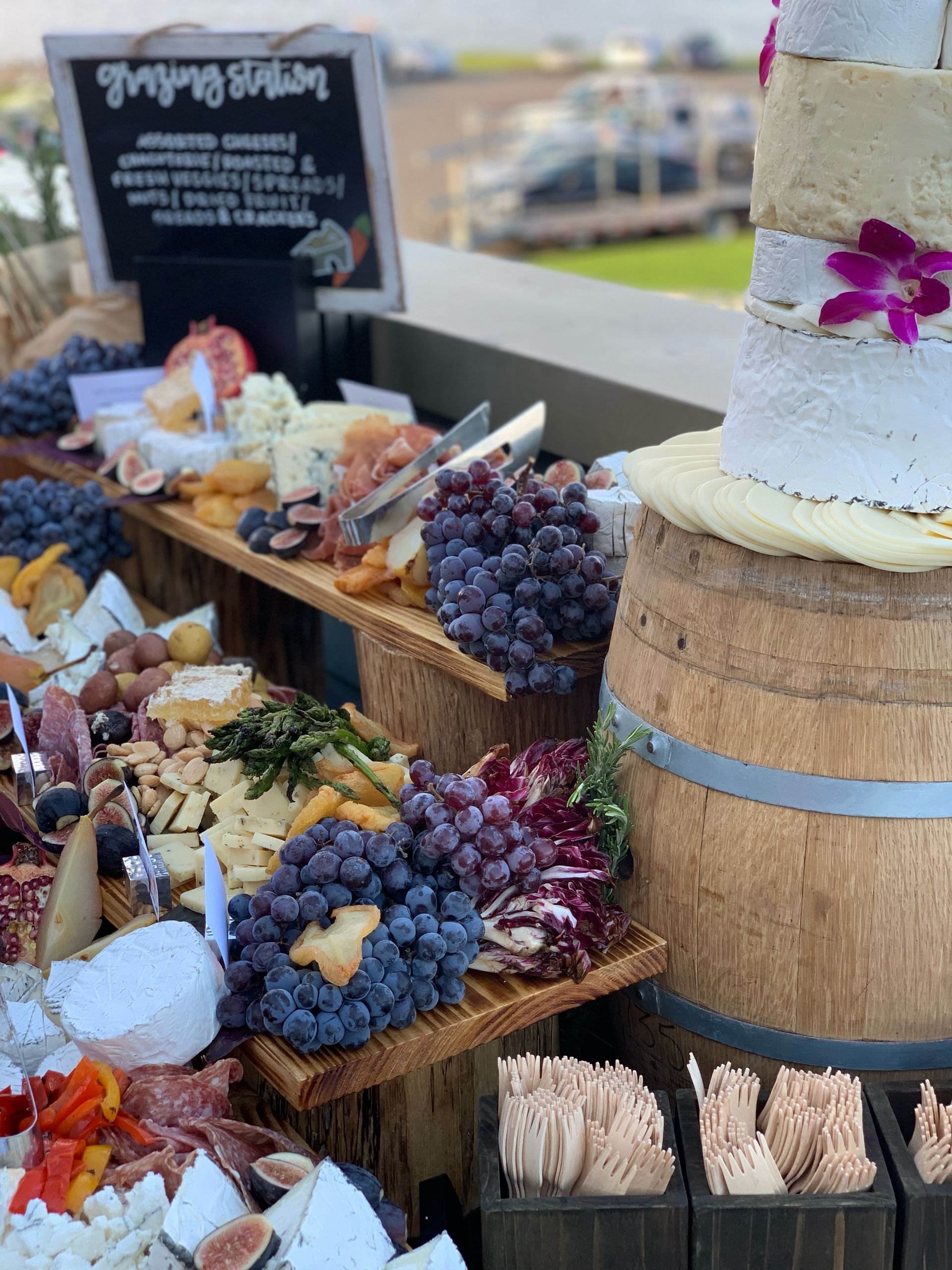 Cheese and charcuterie display on tiered wooden boards, with grapes, figs, and crackers.