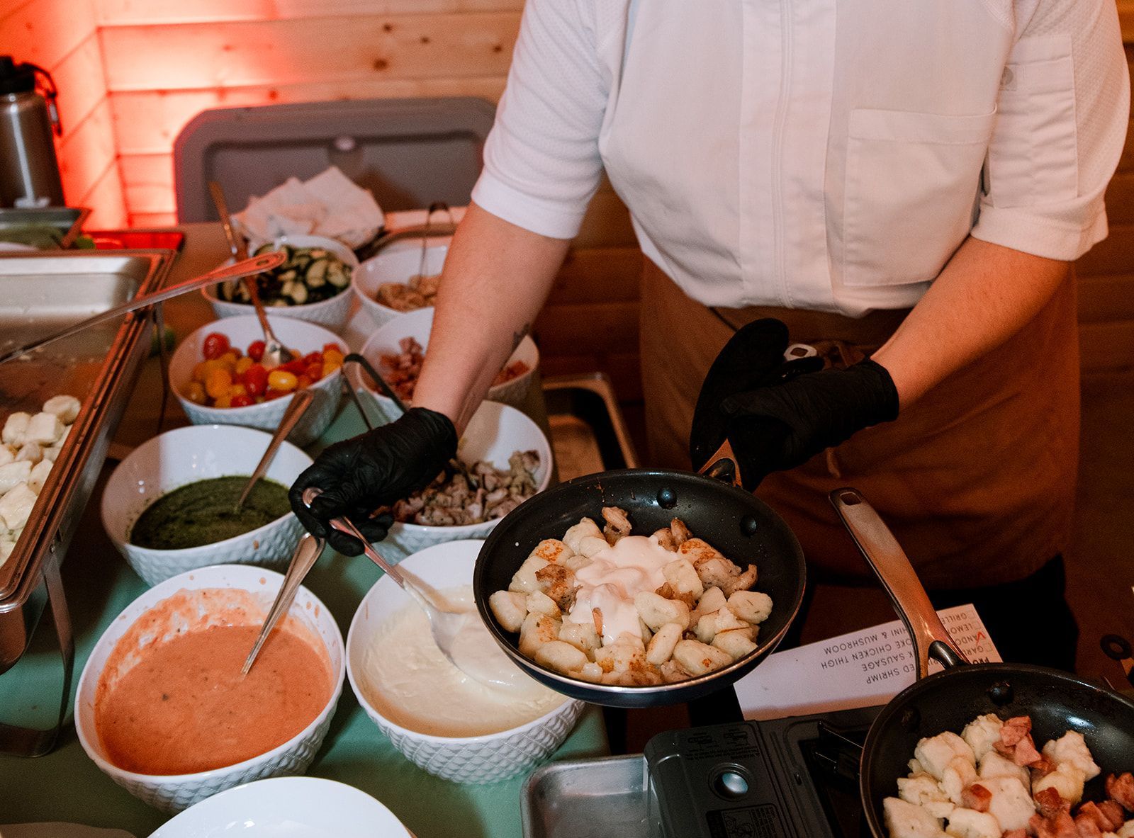 Chef serving buffet with bowls of colorful dishes on a table.