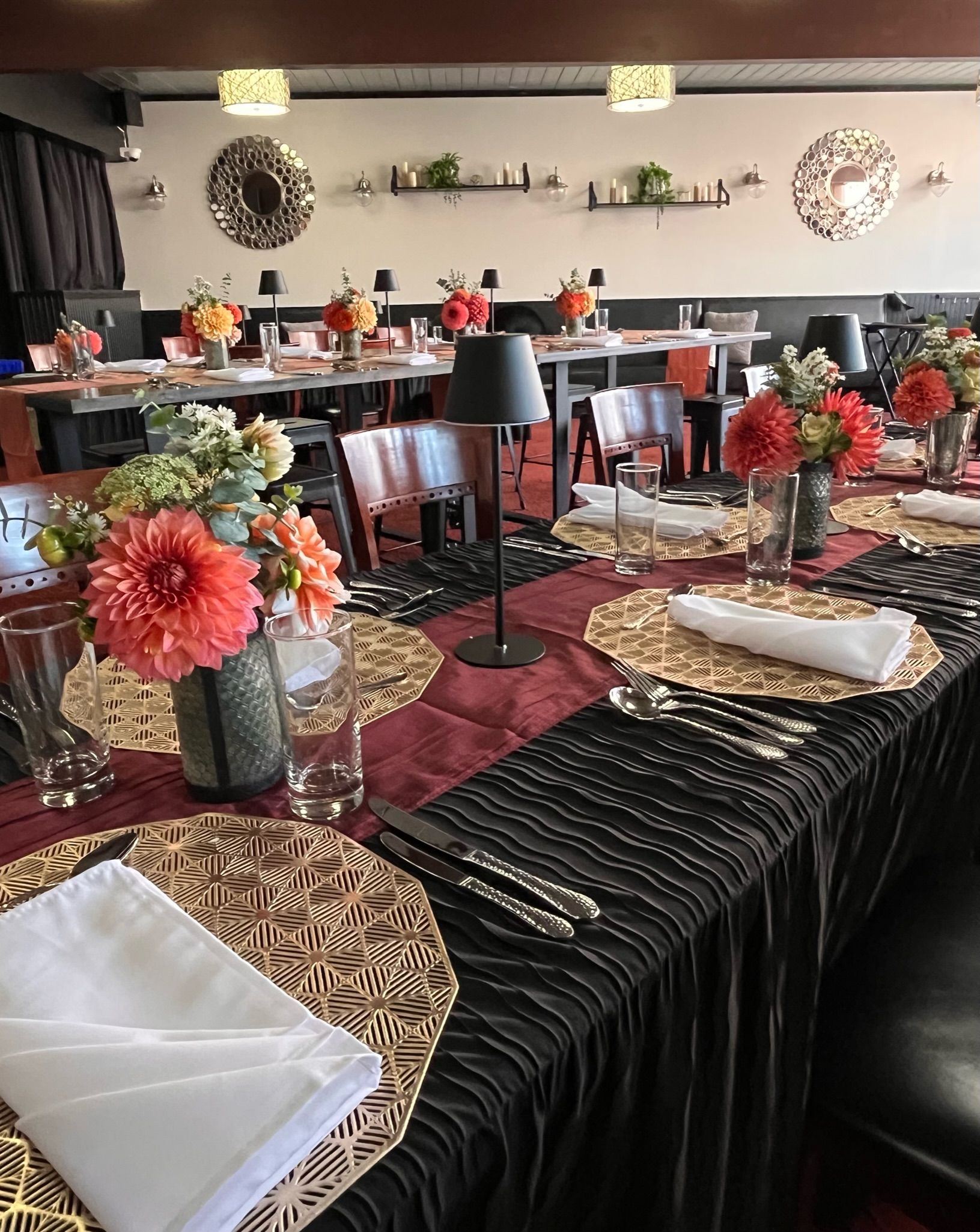 Formal dining table set with flowers, silverware, and place settings. Restaurant setting with red and black accents.