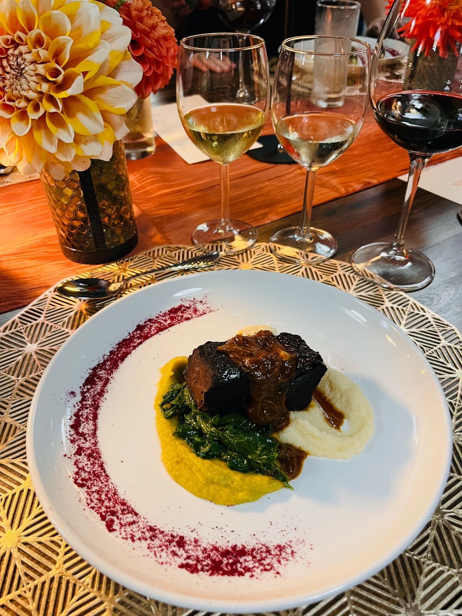 Outdoor pizza oven setup with white tablecloths, food, and greenery, on a sunny day.
