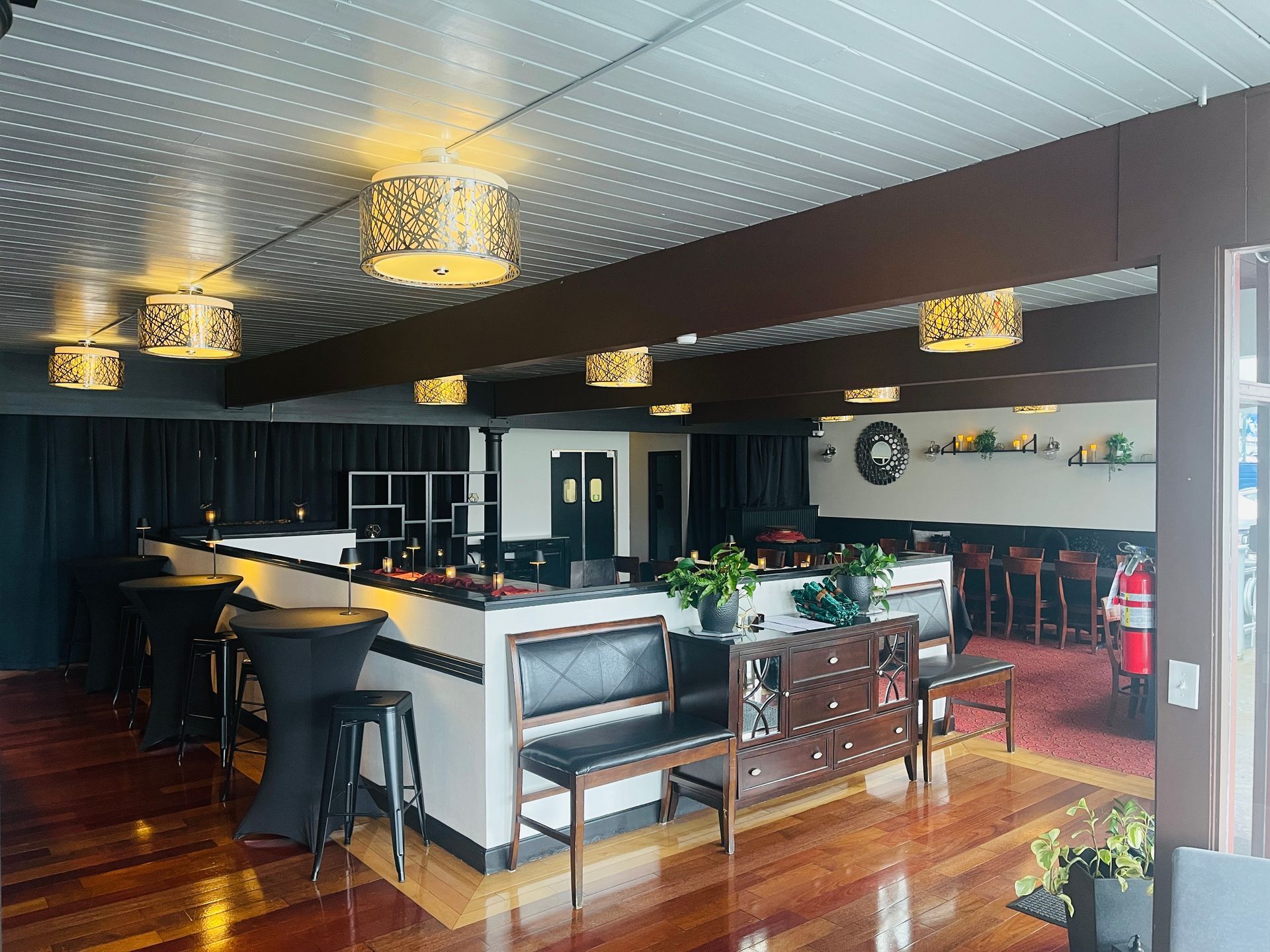 Interior of a bar with ornate ceiling lights, seating, and a bar area with black and white design.