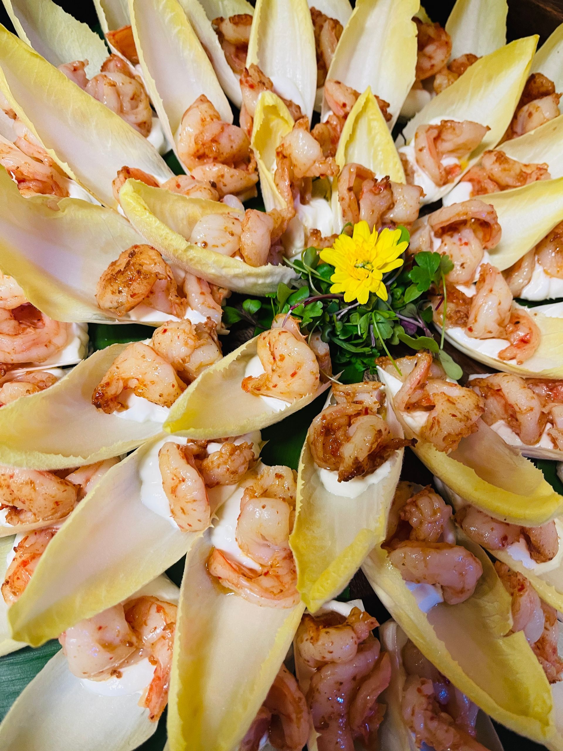 Shrimp appetizers served on endive leaves, arranged in a circle on a platter.