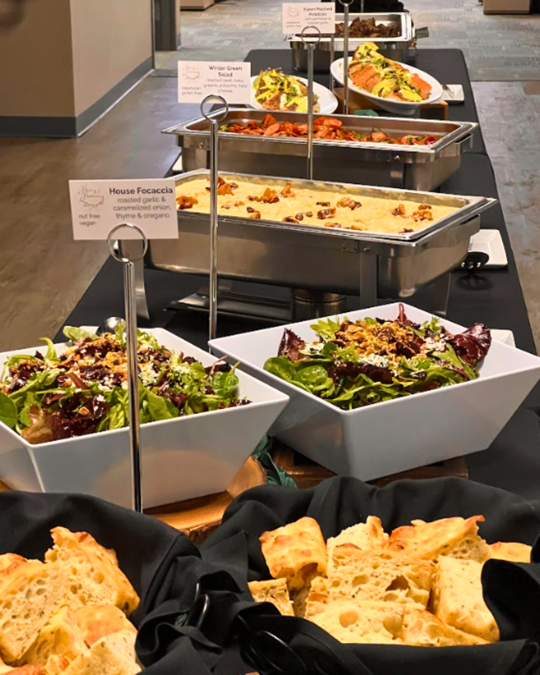 Buffet table with various dishes: salads, casseroles, and bread.