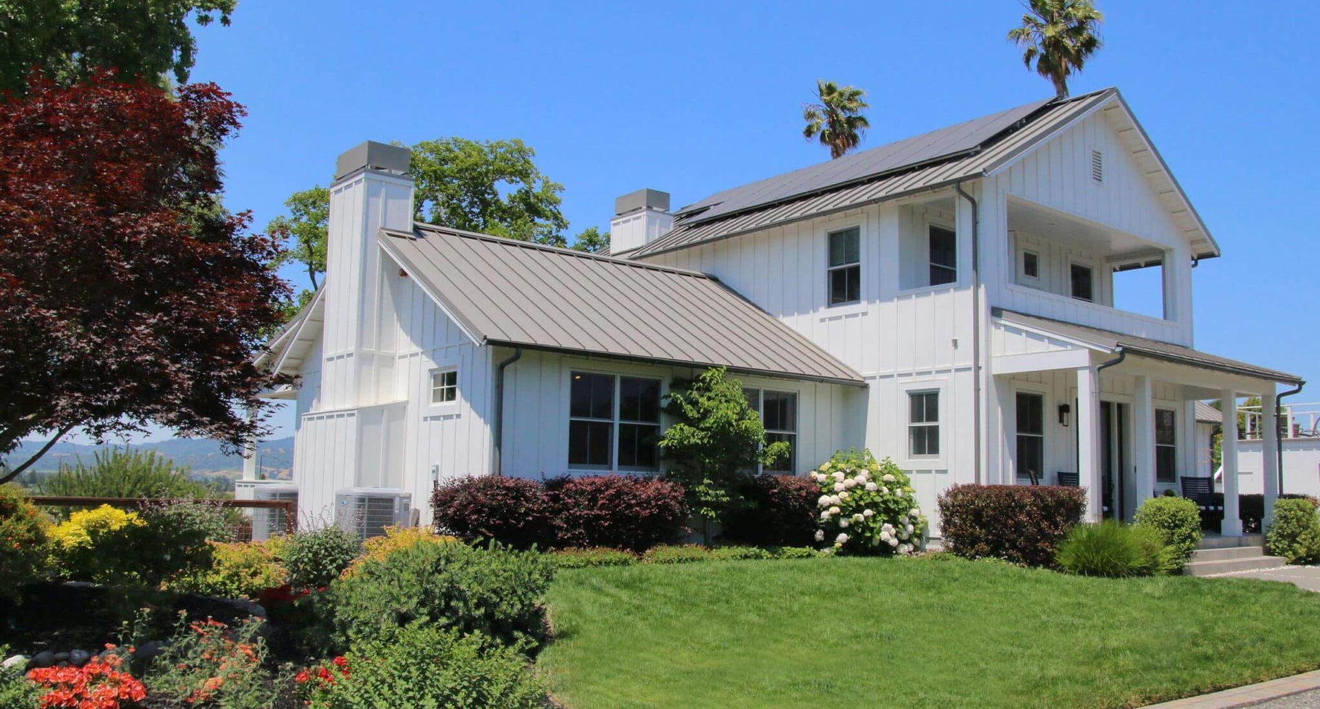 A large white house is sitting on top of a lush green hillside.