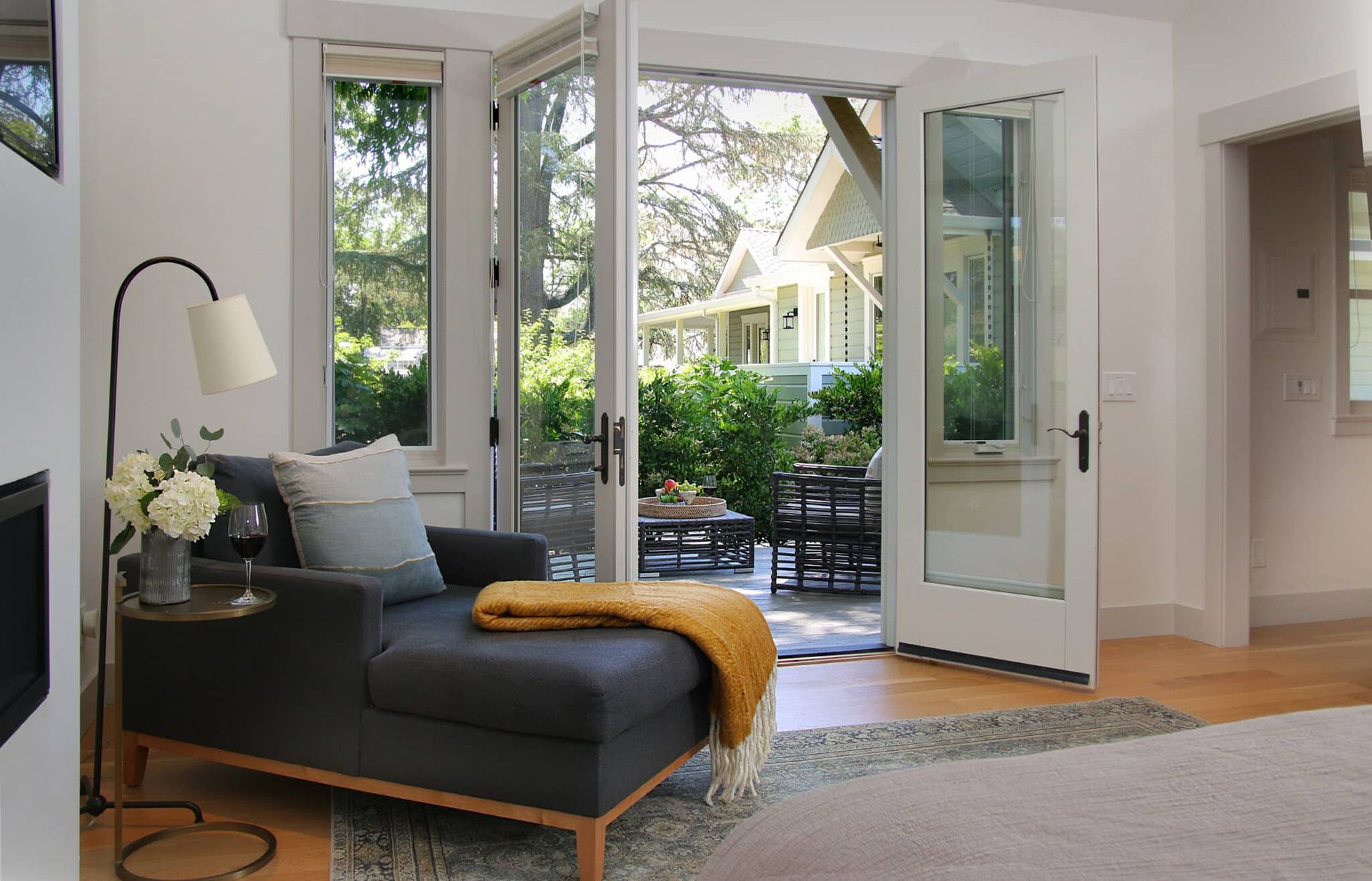 A living room with a couch , chair , lamp and sliding glass doors leading to a patio.