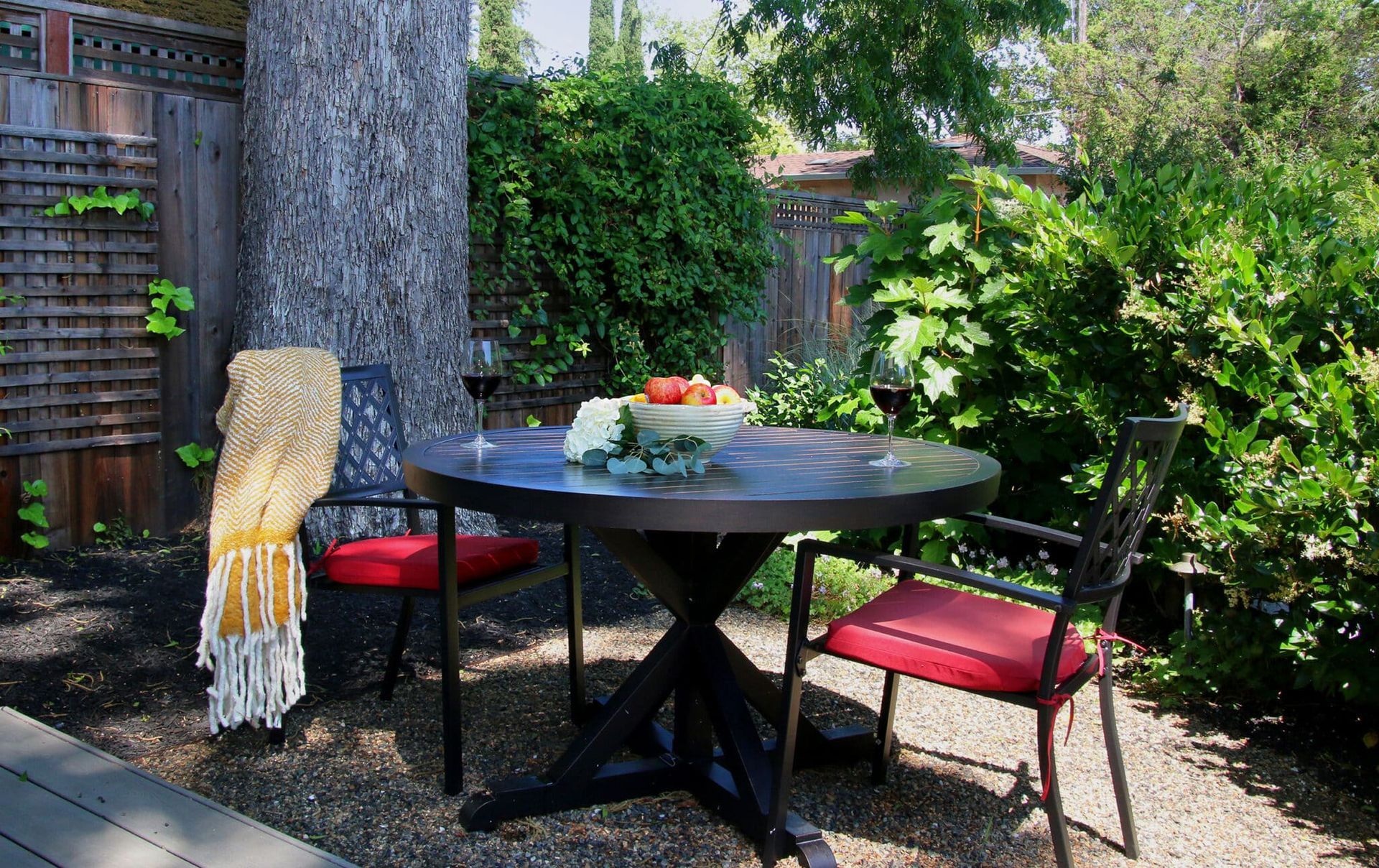 A table and chairs in a backyard with a tree in the background