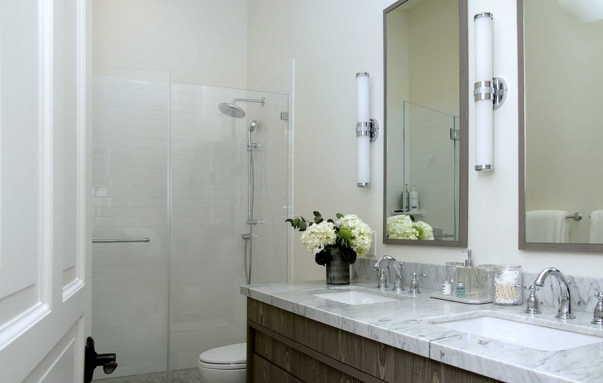 A bathroom with two sinks , a toilet and a shower.