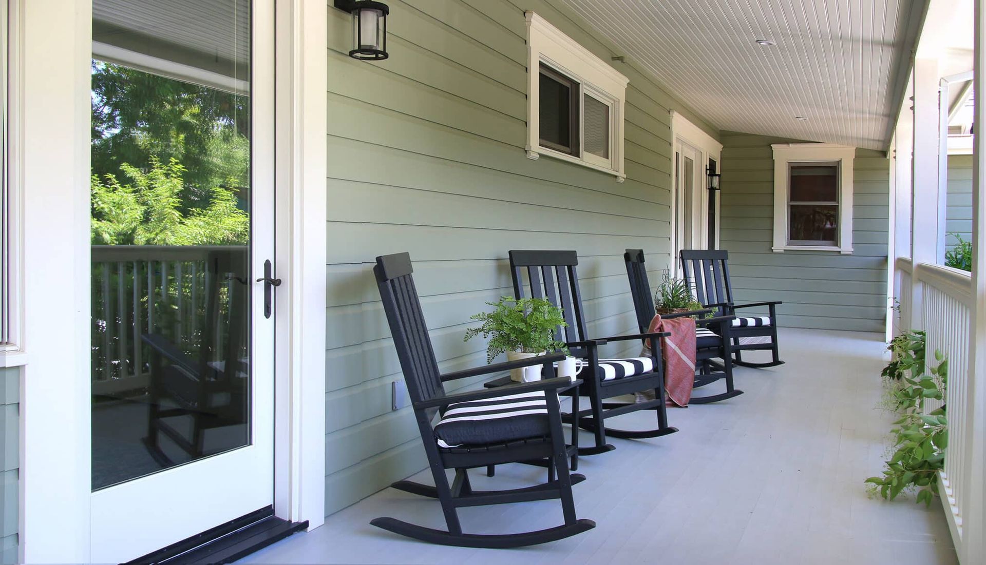 A porch with rocking chairs and a potted plant