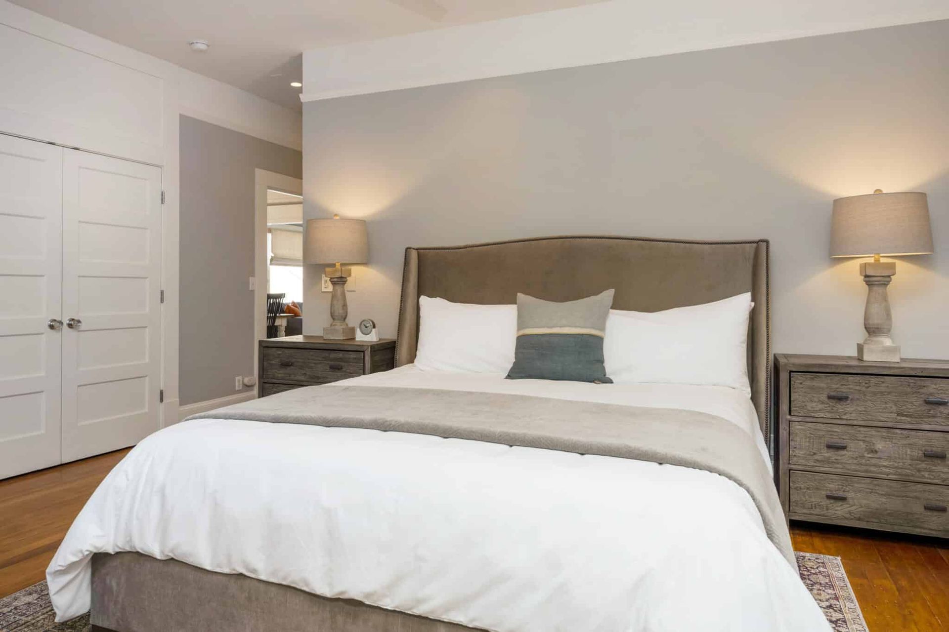 A bedroom with a bed , nightstands , lamps and a dresser.