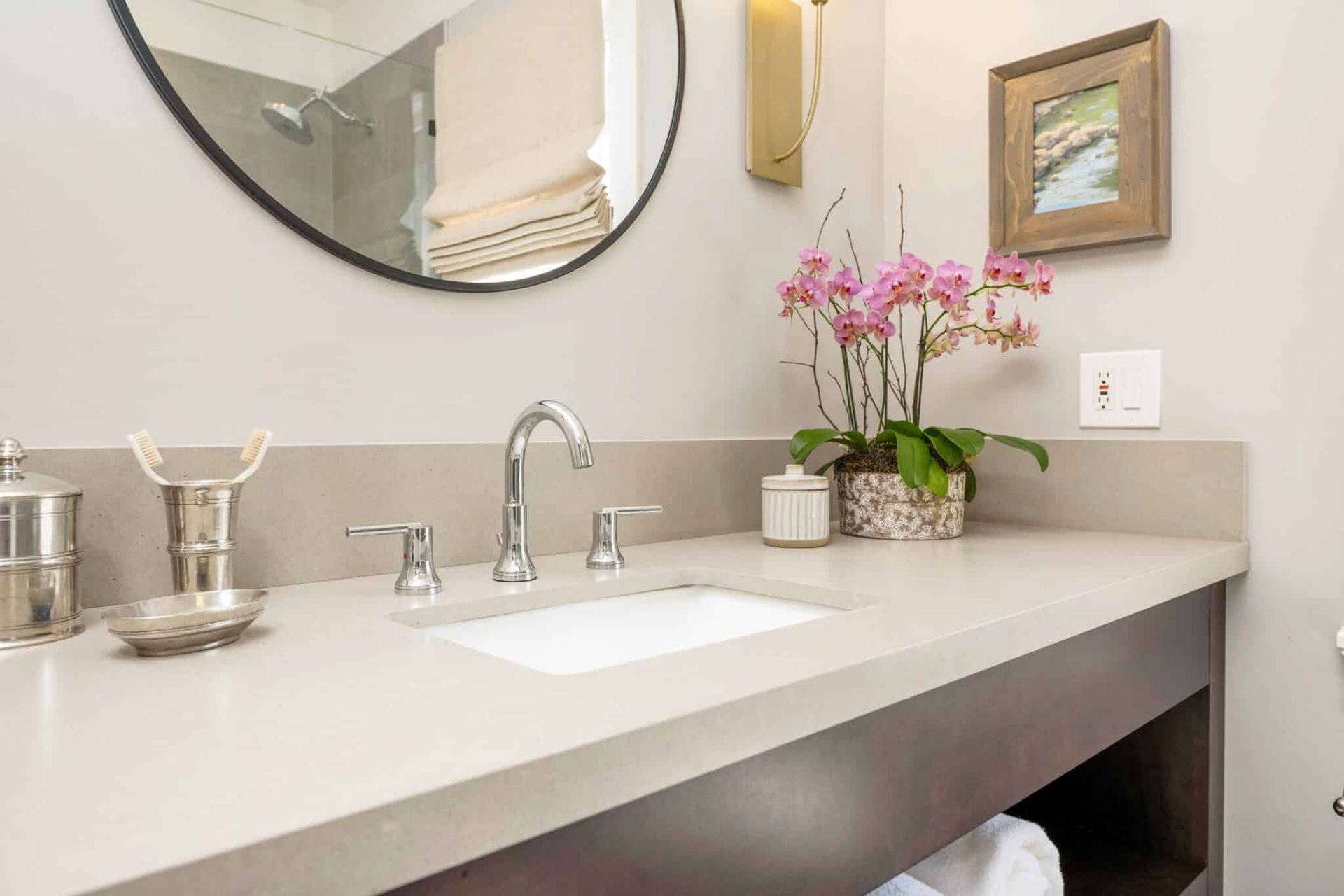 A bathroom with a sink , mirror and flowers on the counter.
