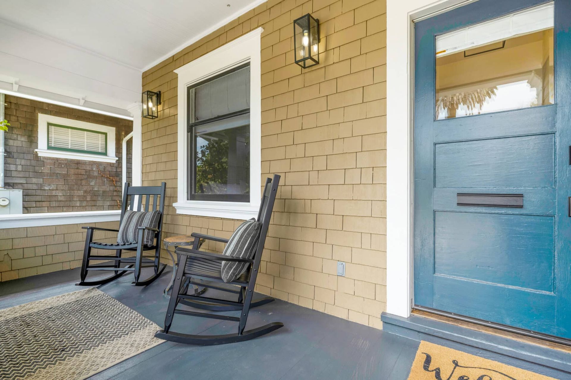 There are two rocking chairs on the porch of a house.