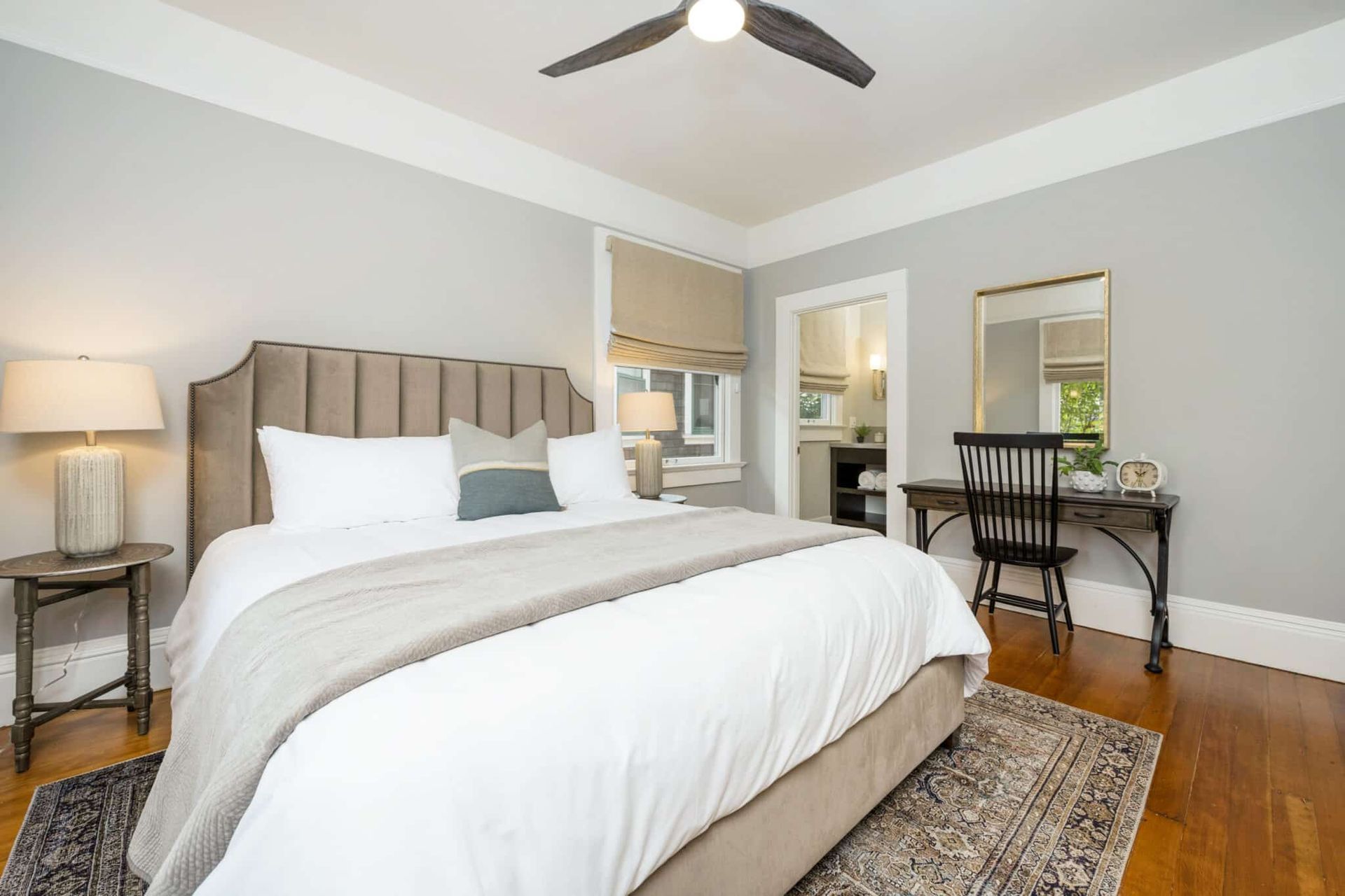 A bedroom with a bed , desk , chair and ceiling fan.