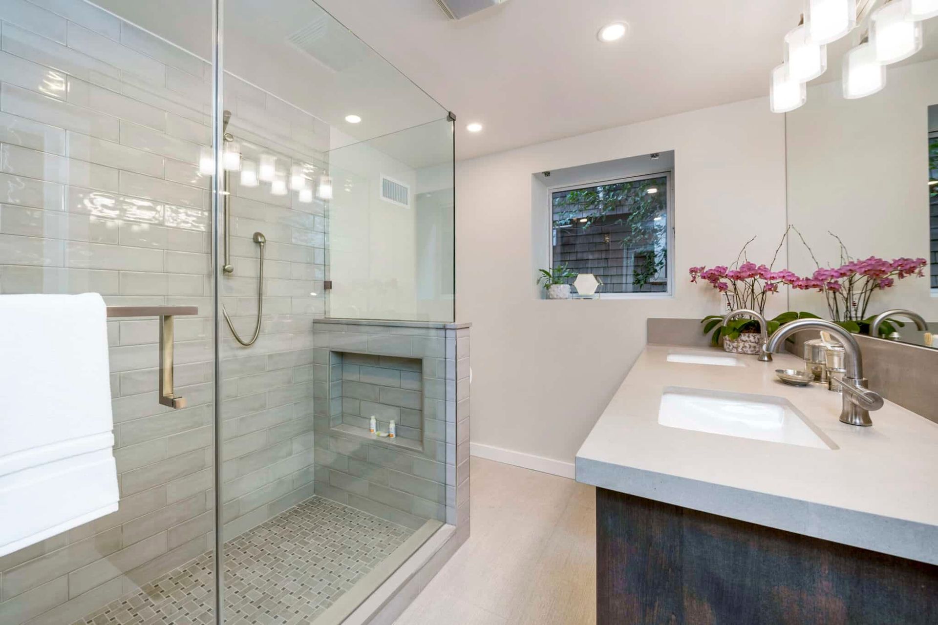 A bathroom with a walk in shower , sink and mirror.