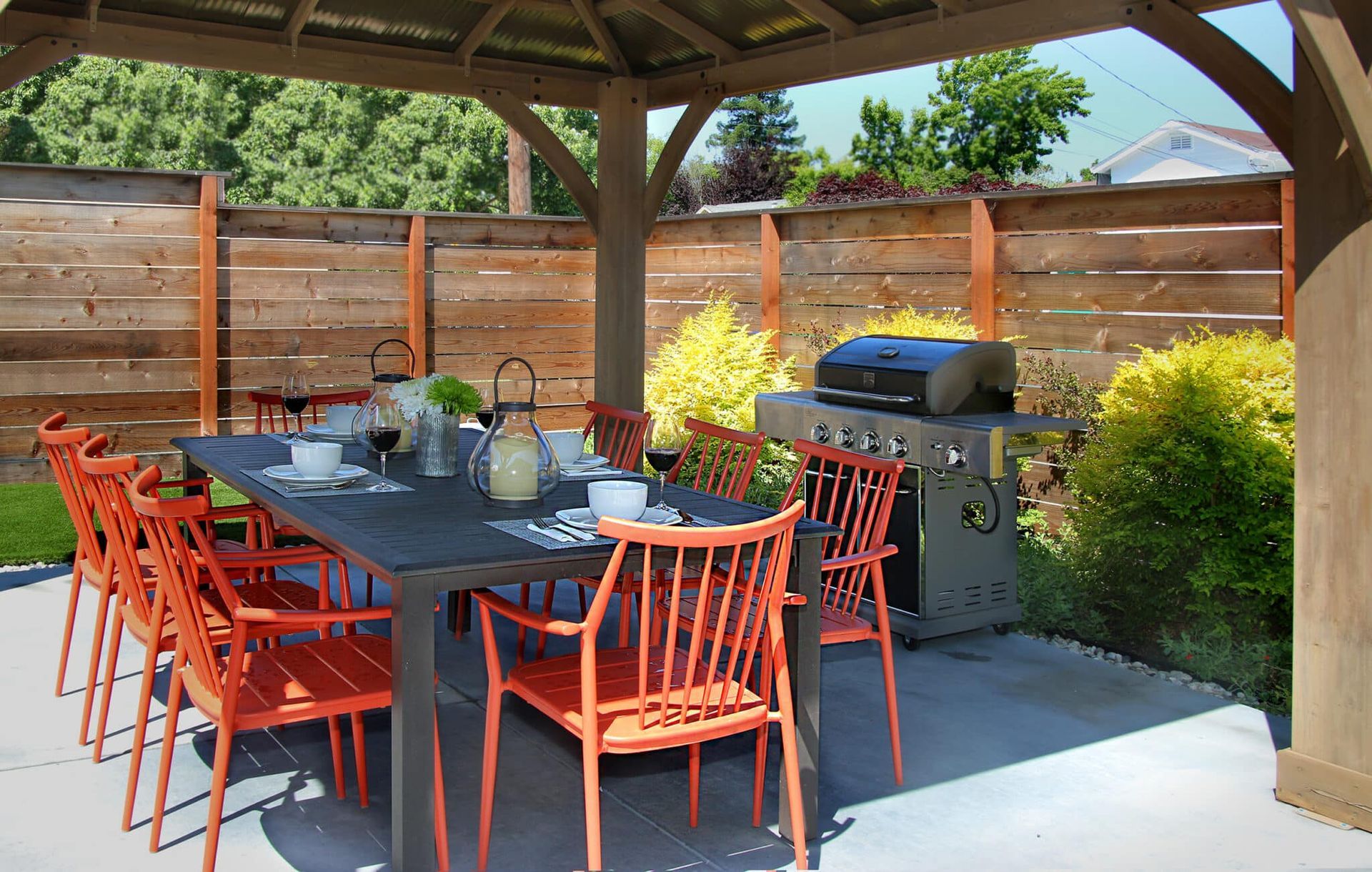 A table and chairs under a gazebo with a grill
