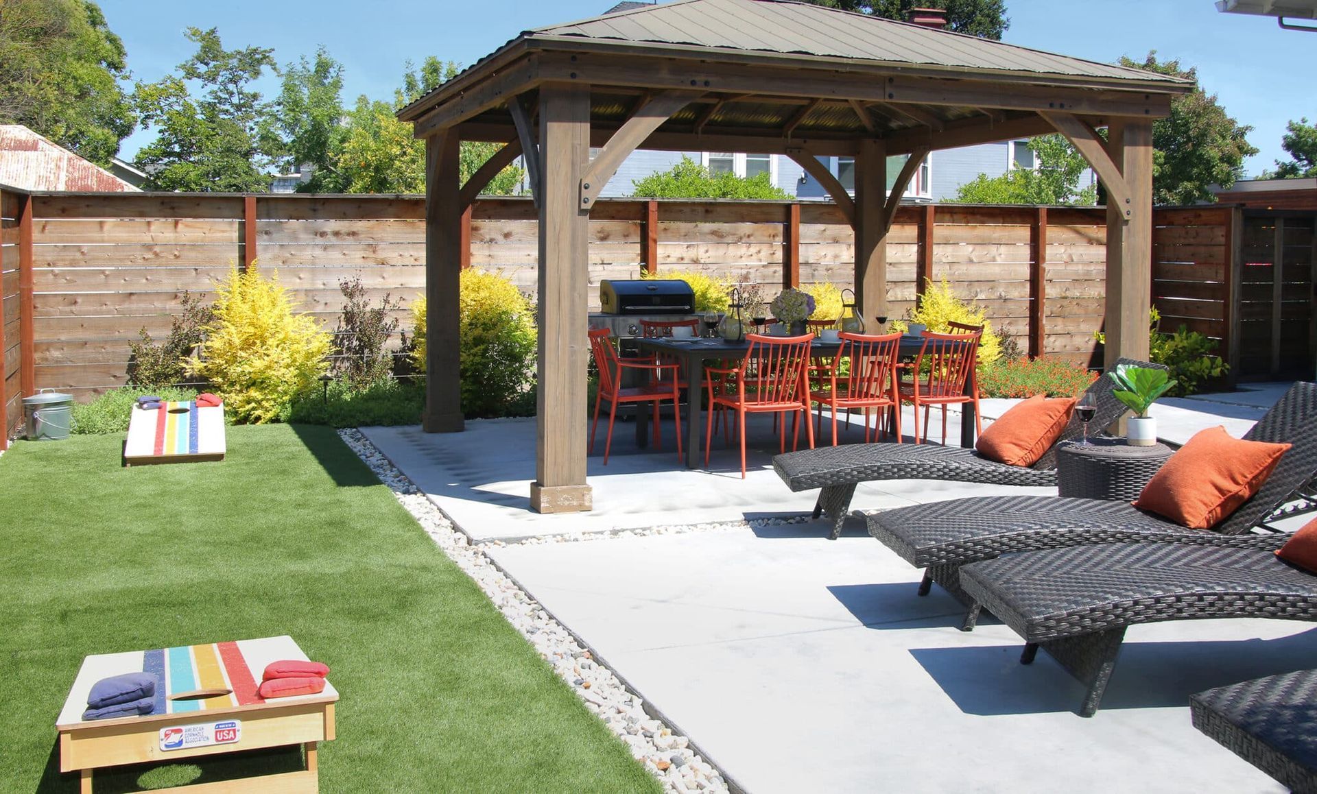 A backyard with a gazebo and chairs and a cornhole board