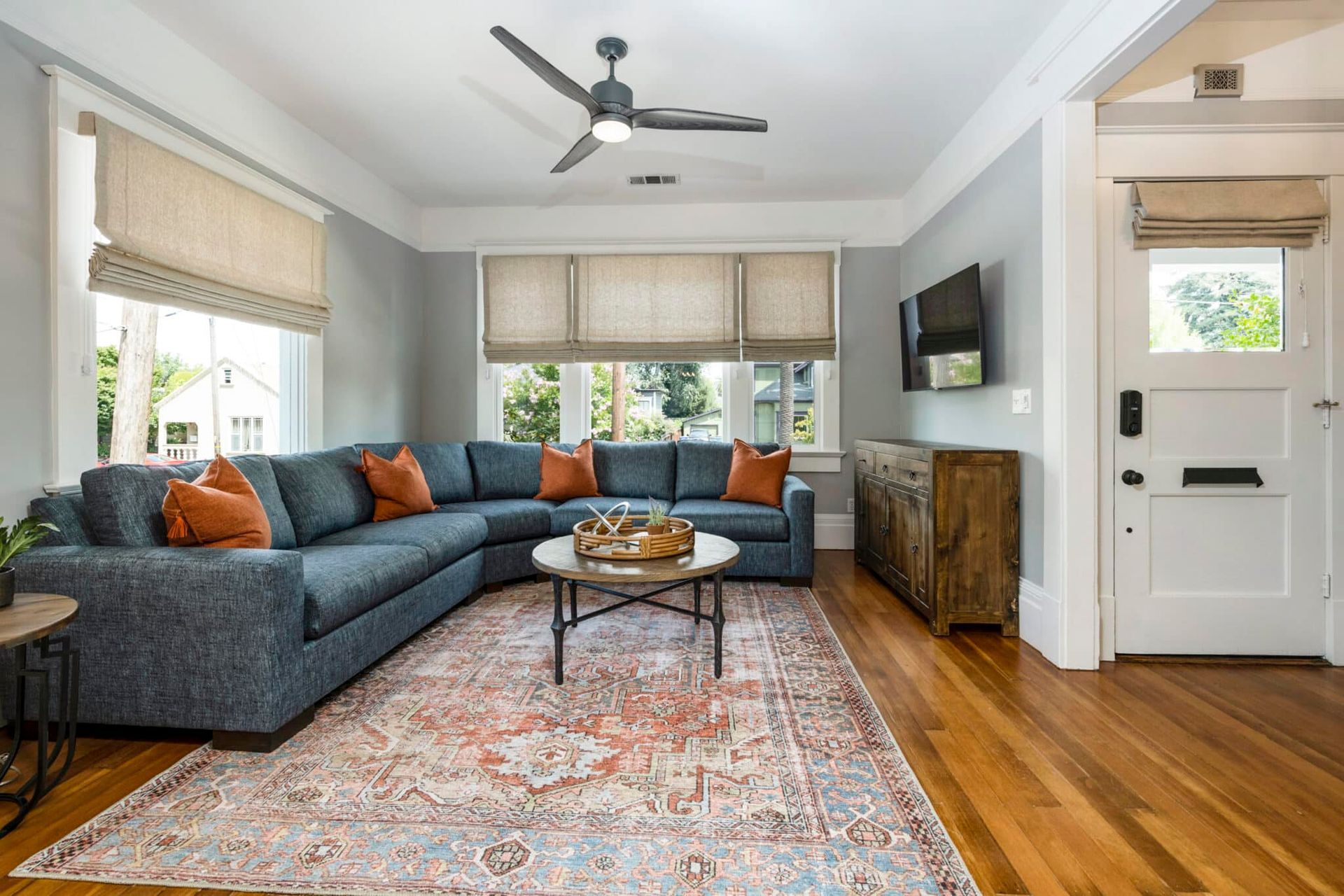 A living room with a large sectional couch and a ceiling fan.