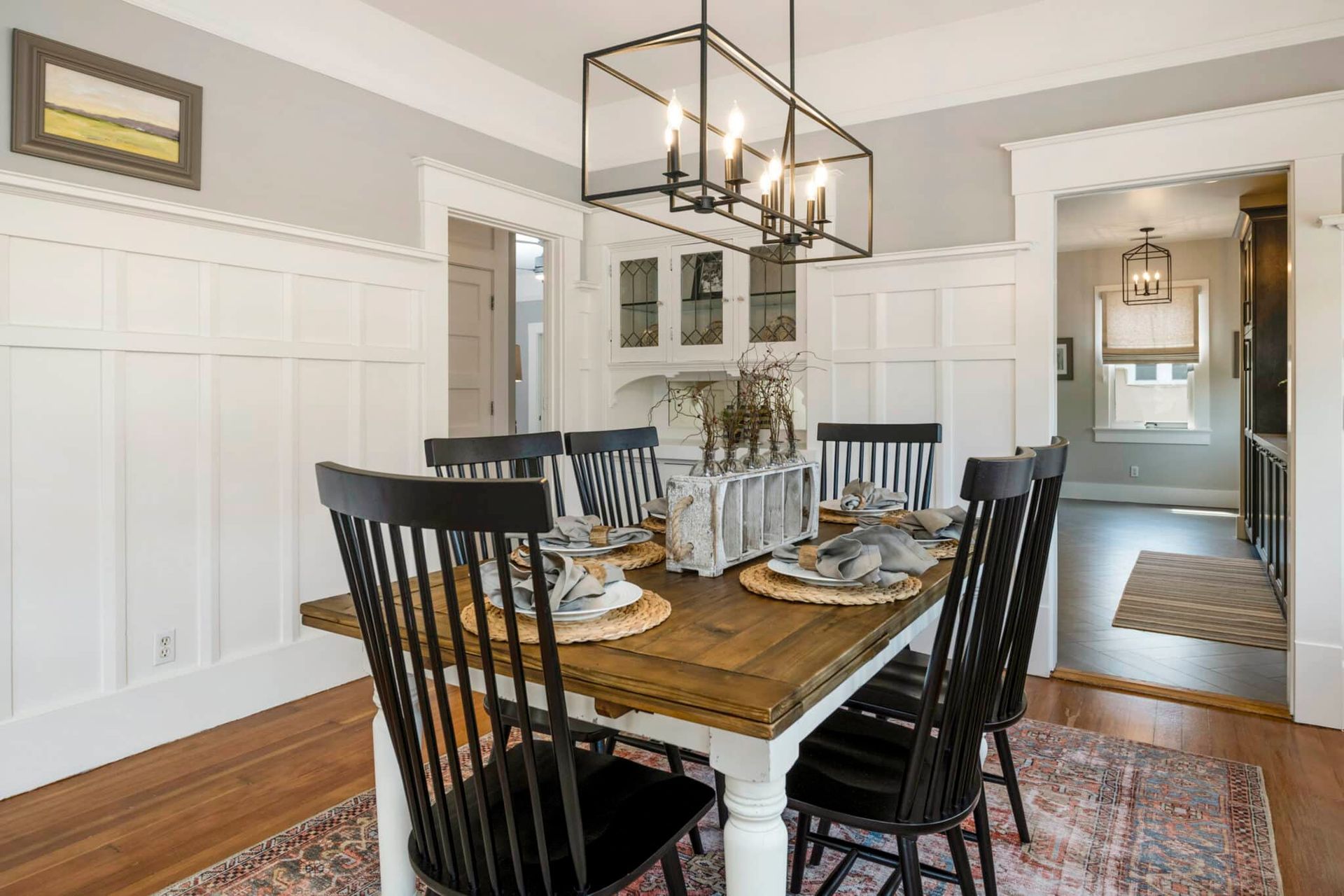 A dining room with a wooden table and chairs and a chandelier.