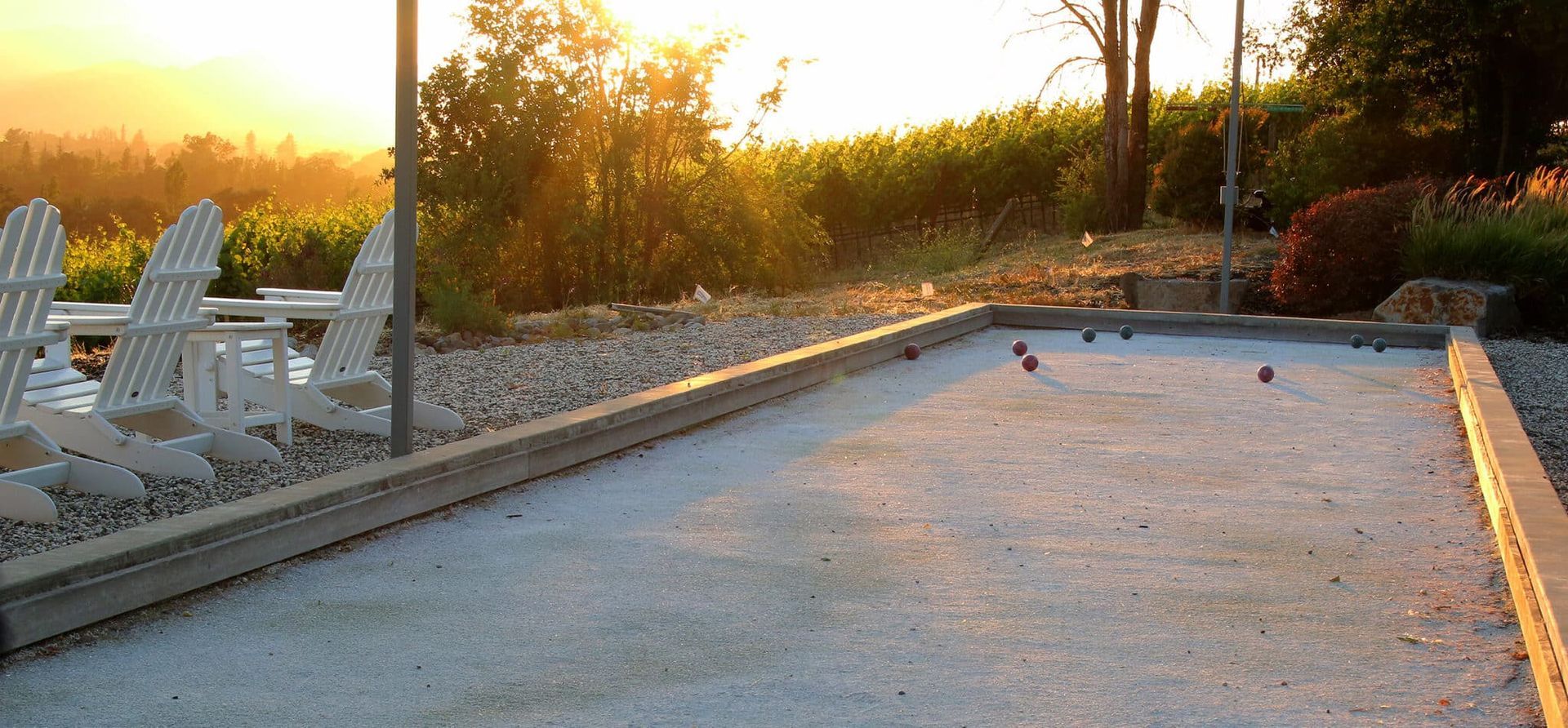 A bocce ball court with chairs in the background at sunset.