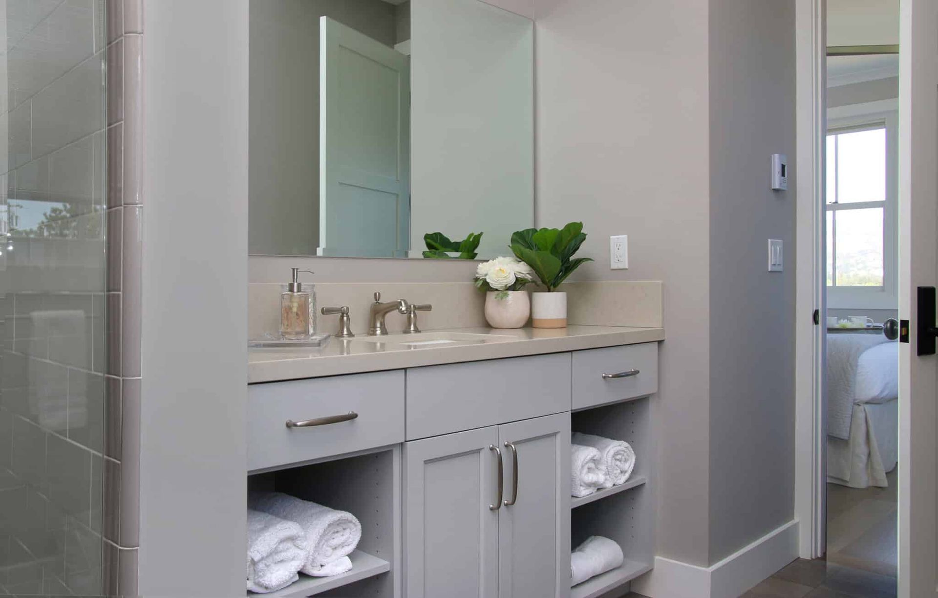 A bathroom with a sink , mirror , towels and a walk in shower.