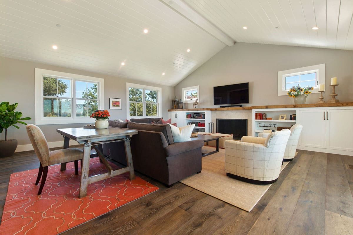 A living room with a couch , chairs , a table and a fireplace.